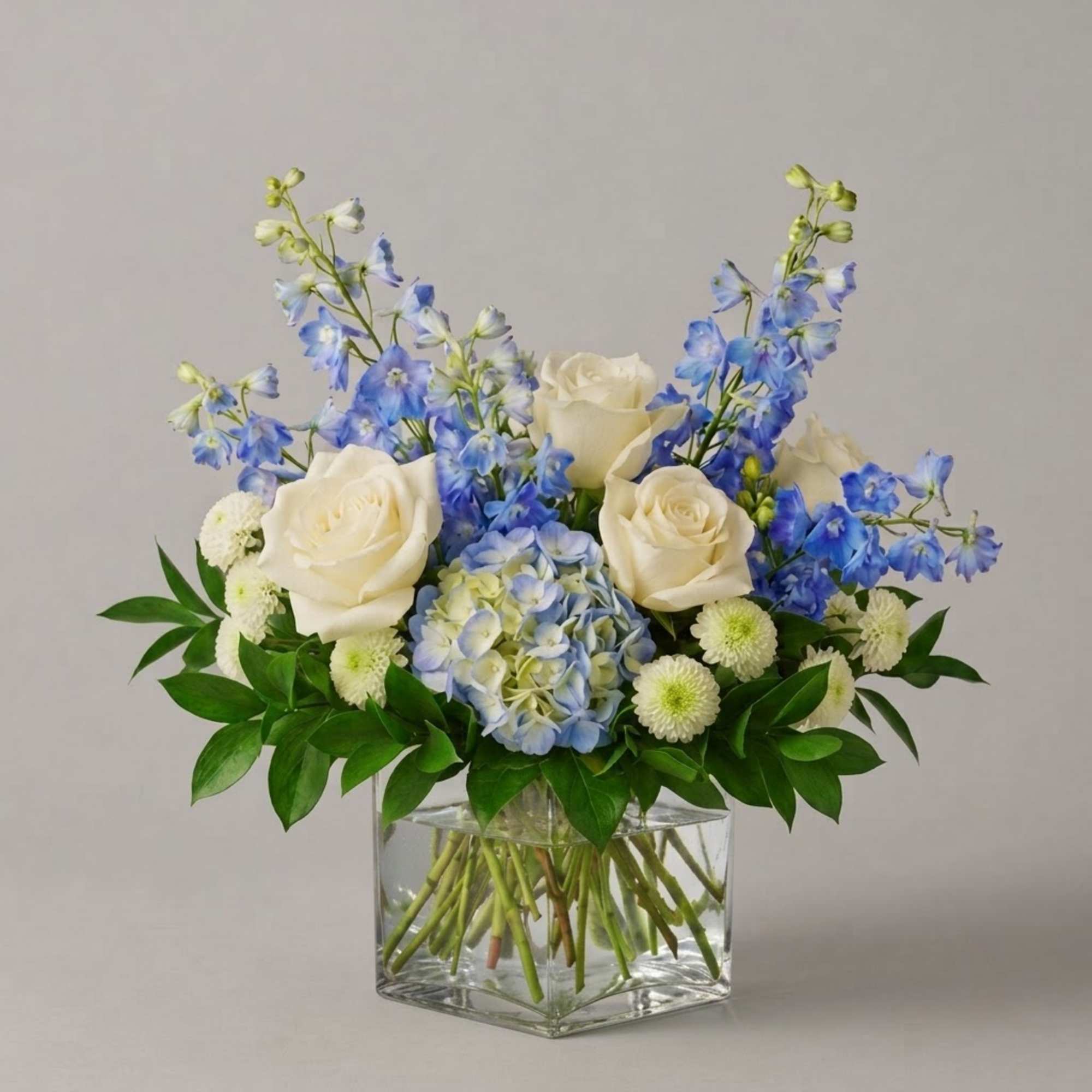 Blue and white floral arrangement in a clear square vase