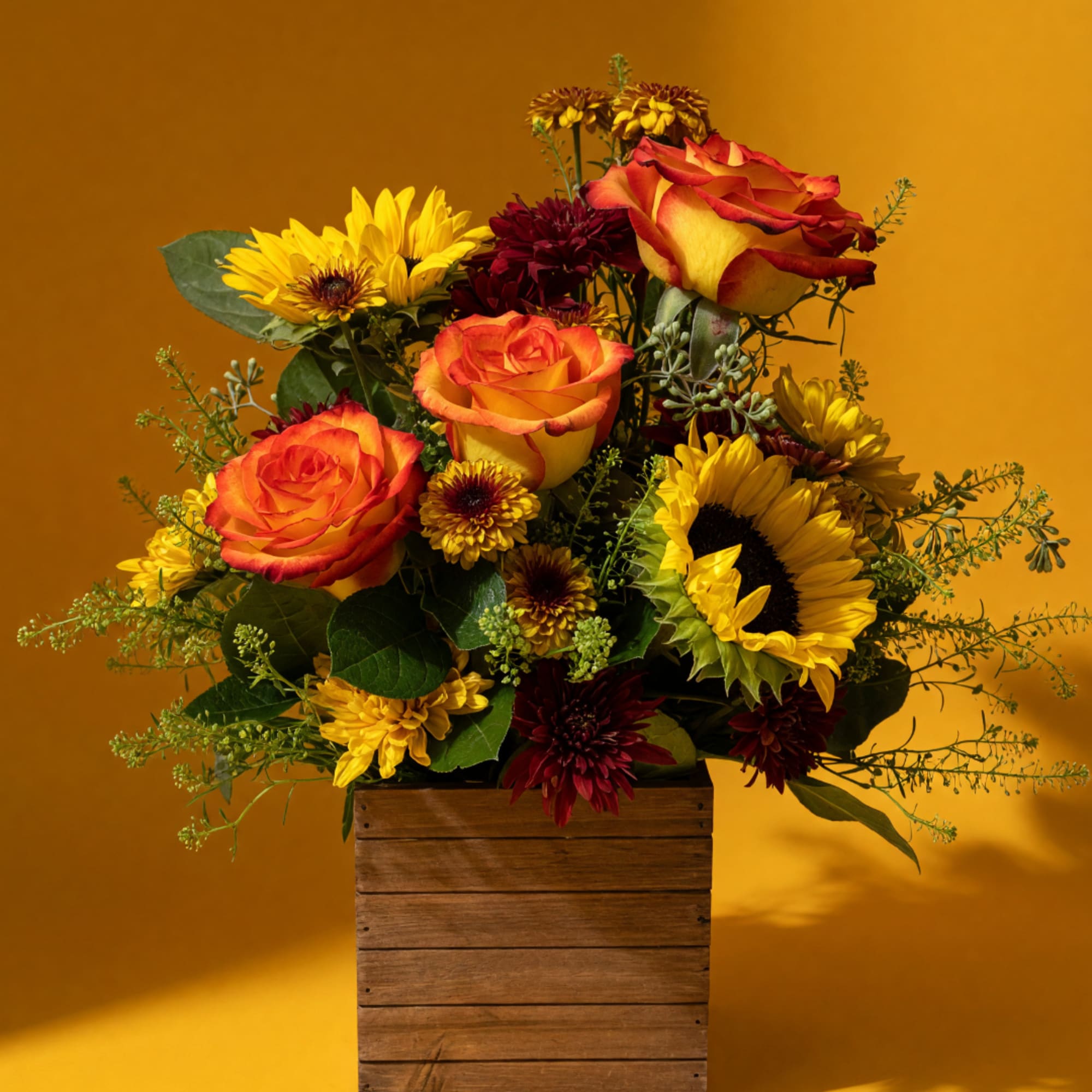 Bouquet of orange roses and yellow sunflowers in a wooden box