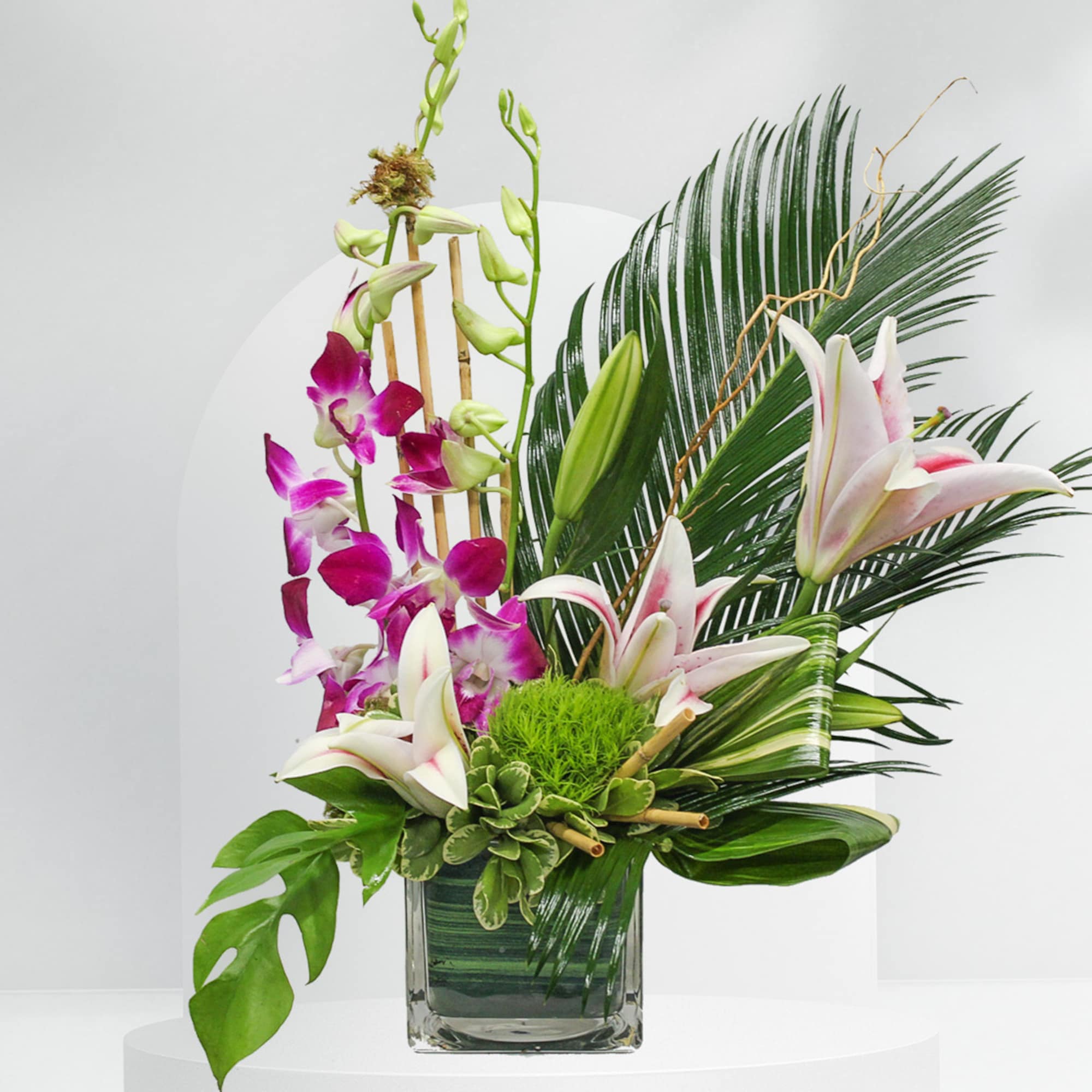 Tropical floral arrangement with orchids and lilies in a glass vase, photo 2 of 2
