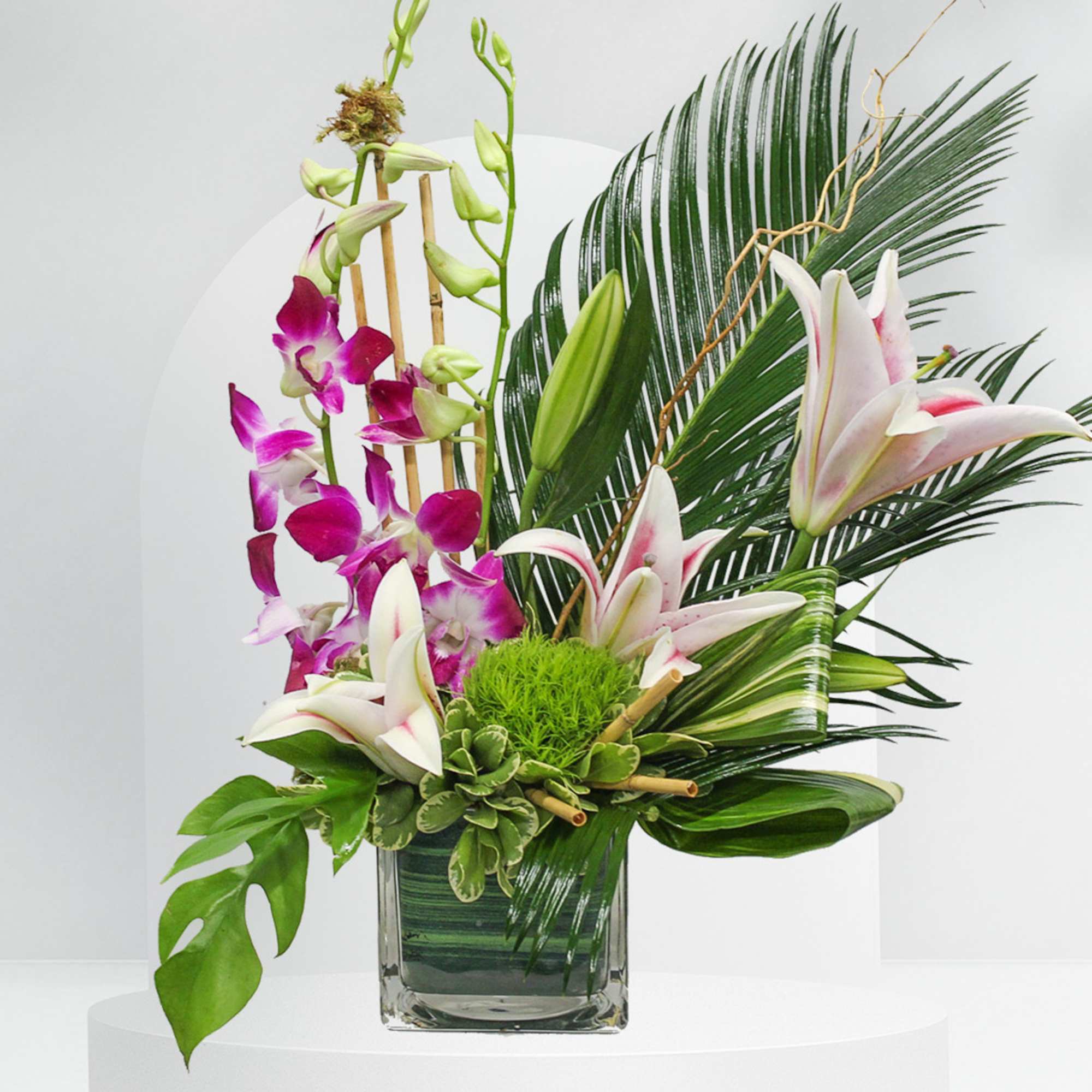 Tropical floral arrangement with orchids and lilies in a glass vase