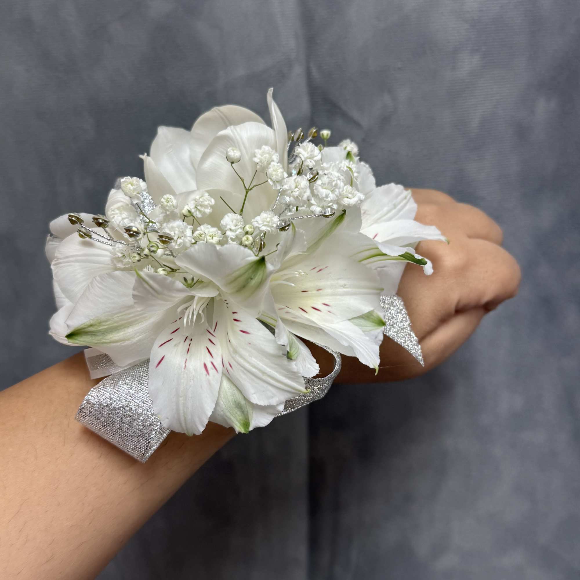 White alstroemeria and tulip wrist corsage with silver ribbon, glitter and pearl