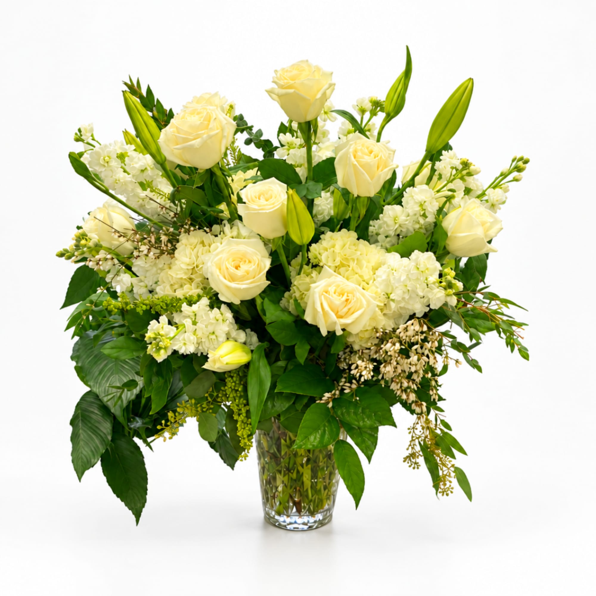 Cream roses and white flowers arranged in a clear glass vase