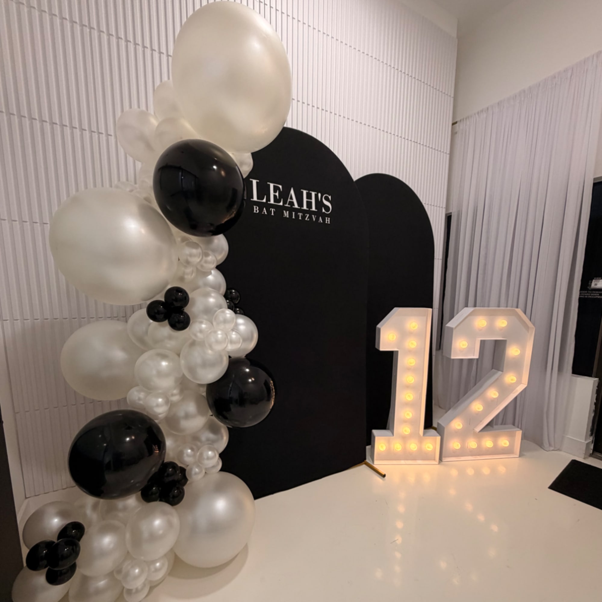 Black and white balloon display with a lit number 12 sign