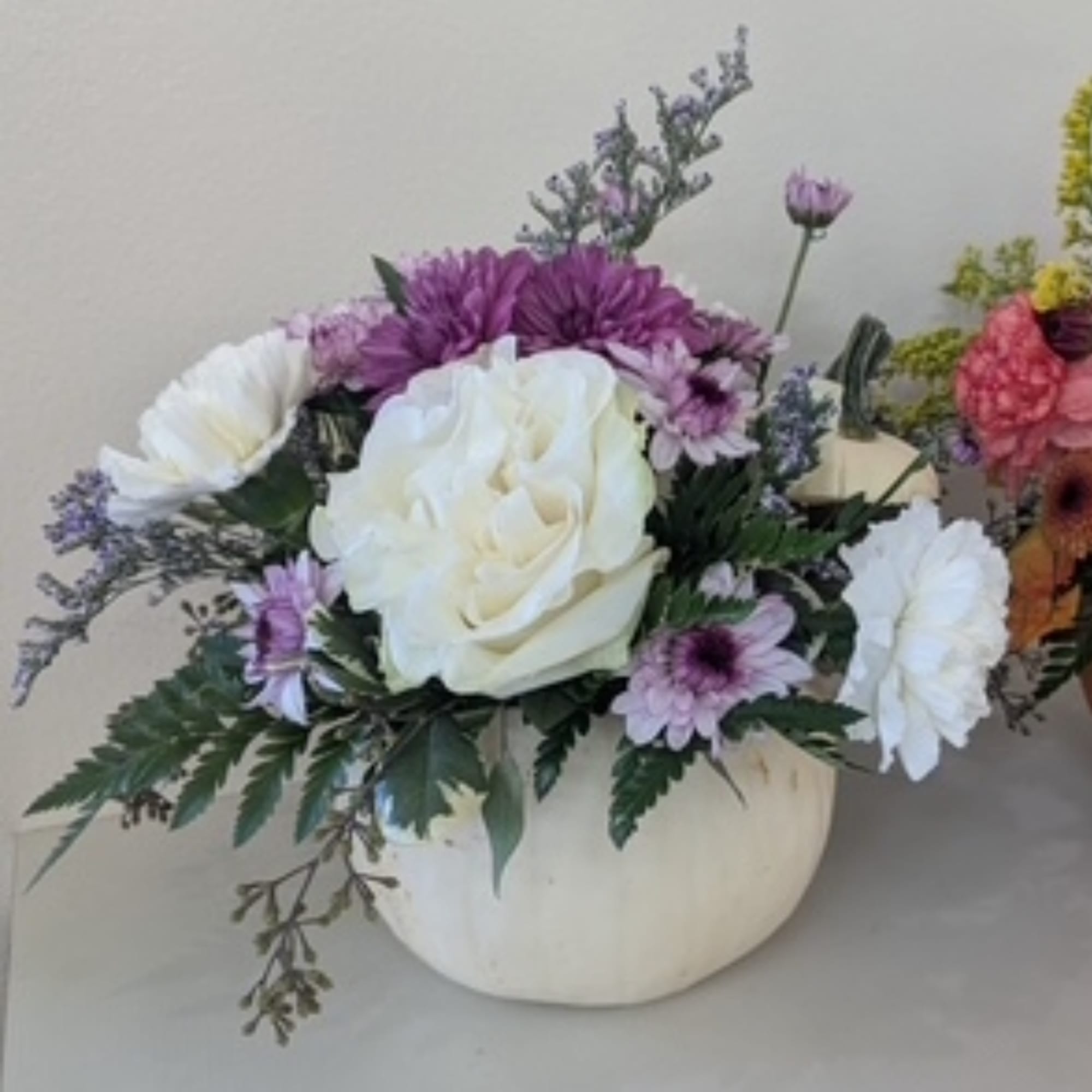 White and purple floral arrangement in a round white vase