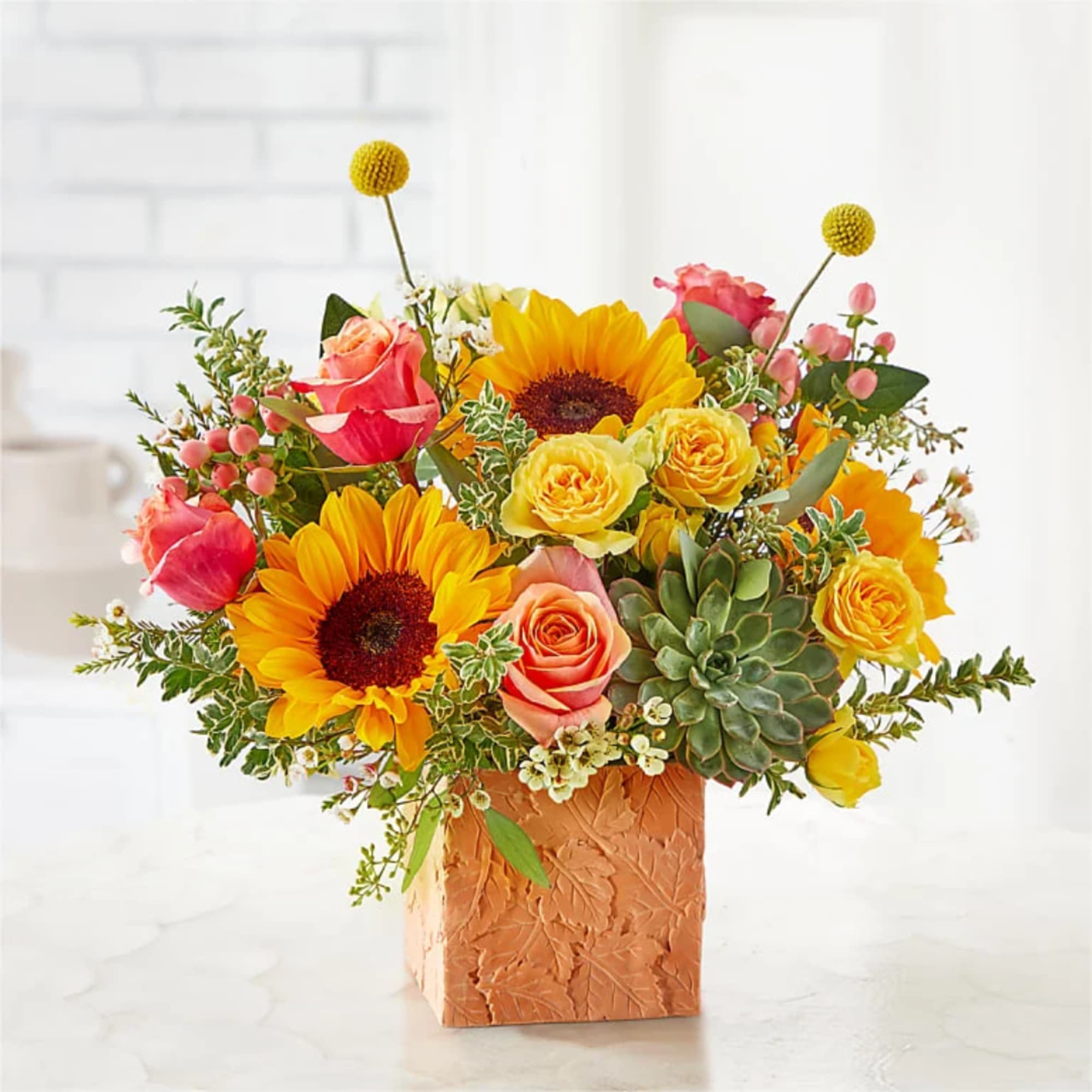 Sunflower and rose arrangement in a textured square vase