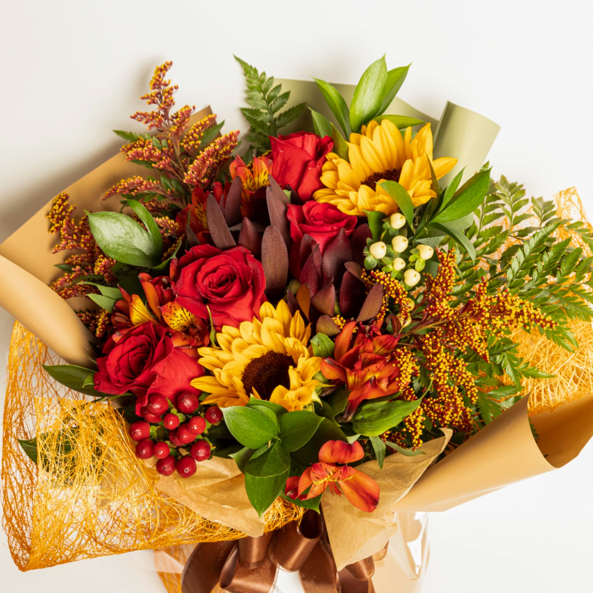 Bouquet of red roses and yellow sunflowers wrapped in tan paper