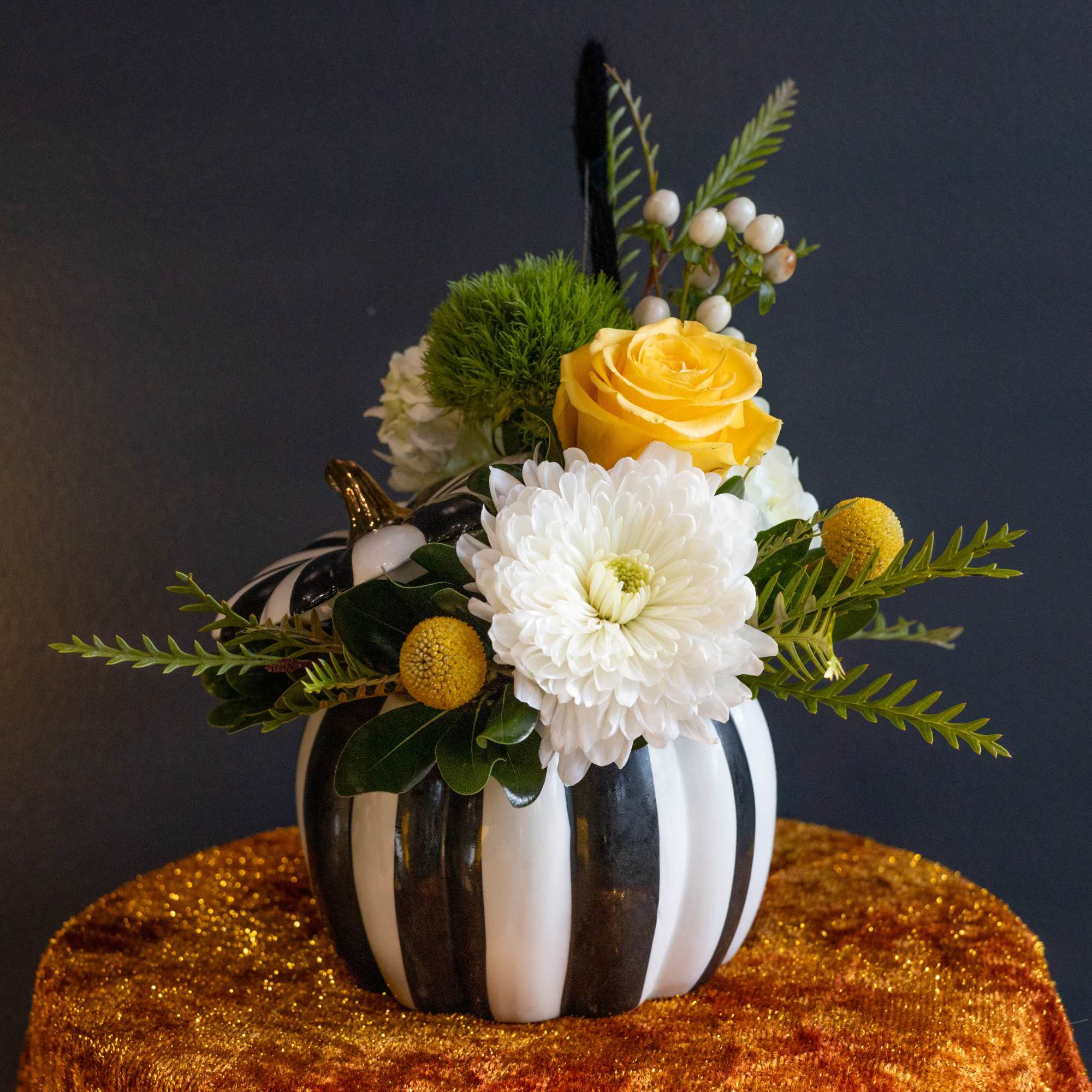Yellow rose and white chrysanthemum arrangement in a striped pumpkin vase