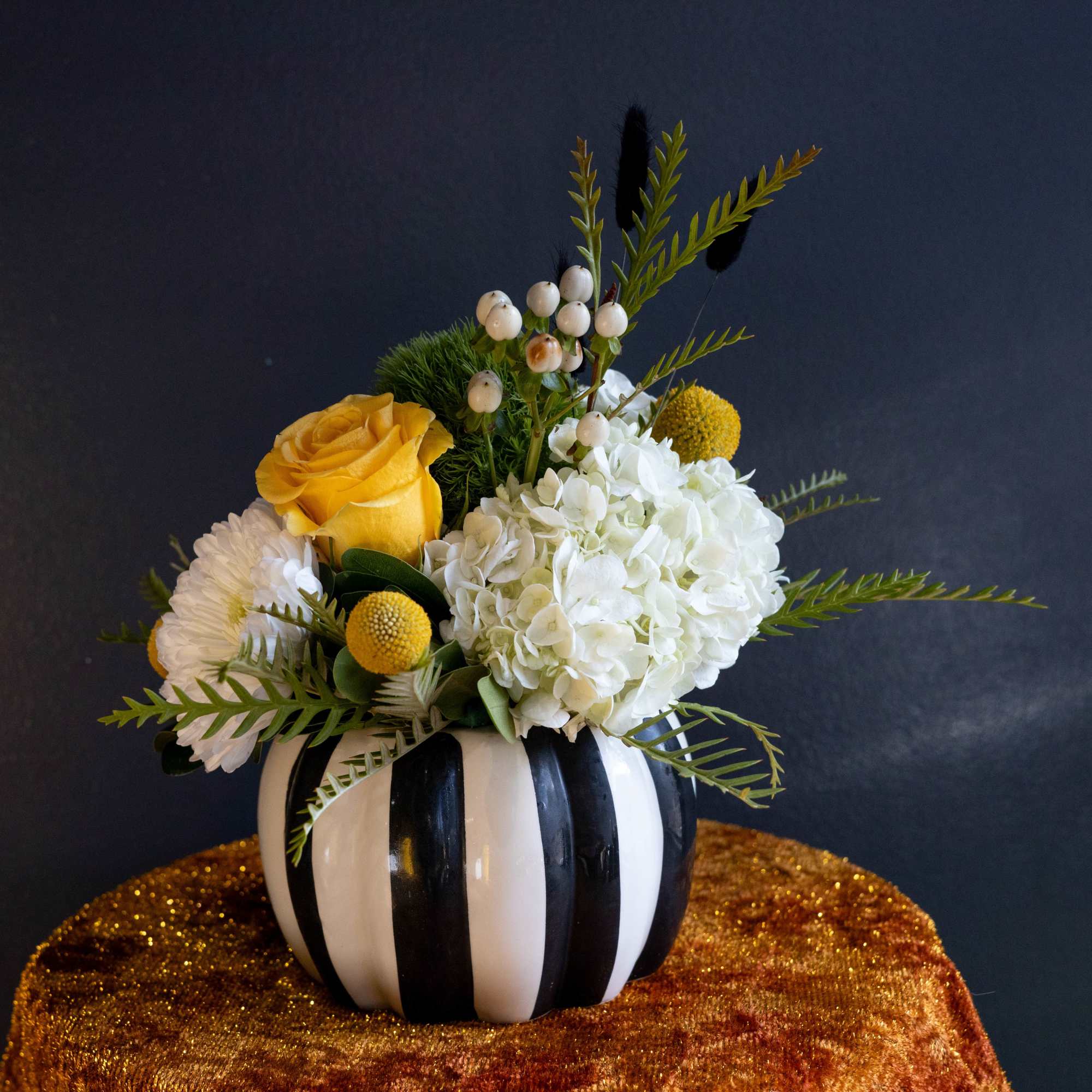 Yellow rose and white hydrangea arrangement in a striped pumpkin vase