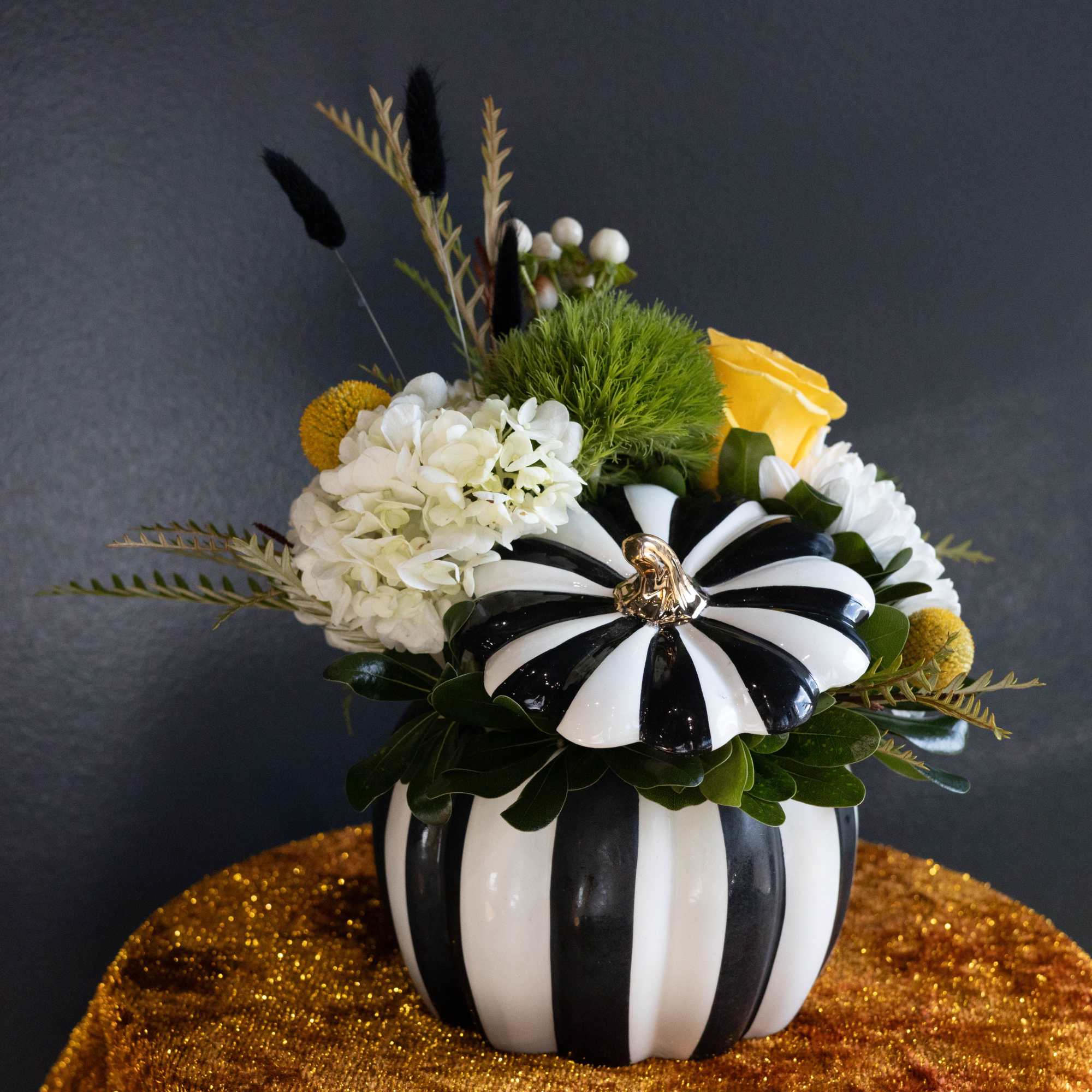 Black-and-white striped pumpkin vase with white and yellow flowers