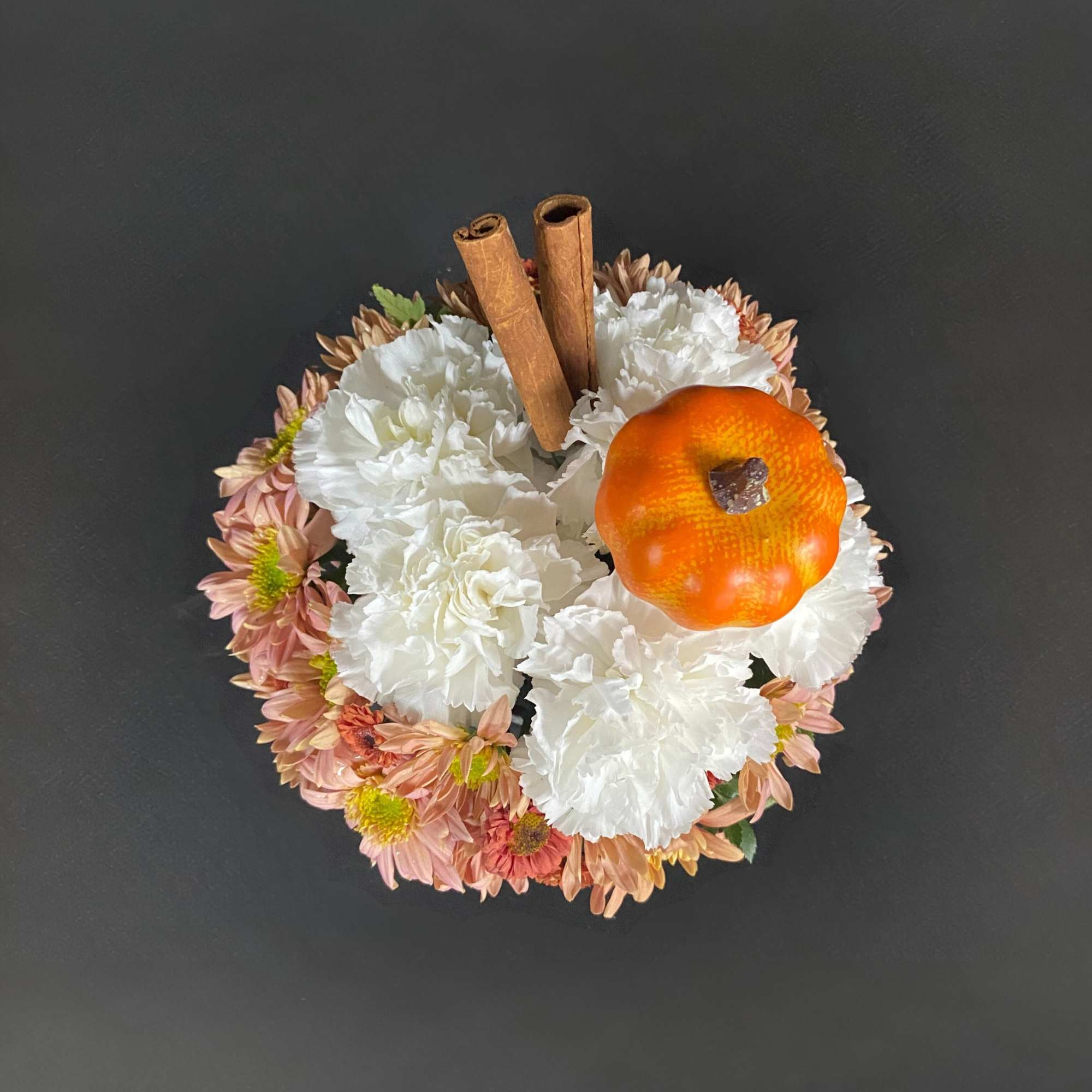 White and peach floral arrangement with cinnamon sticks and a small pumpkin