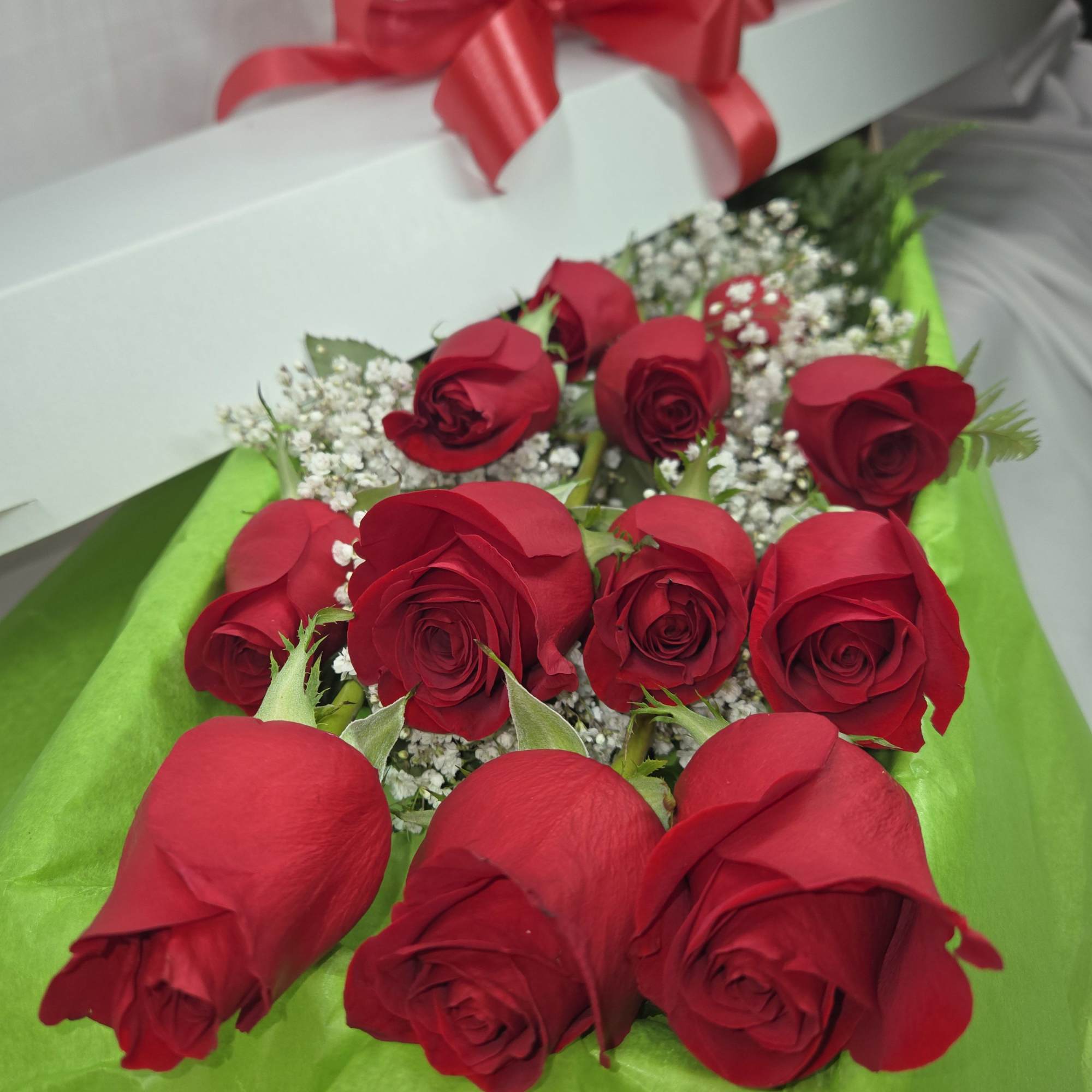 Box of red roses with baby's breath and a red ribbon bow