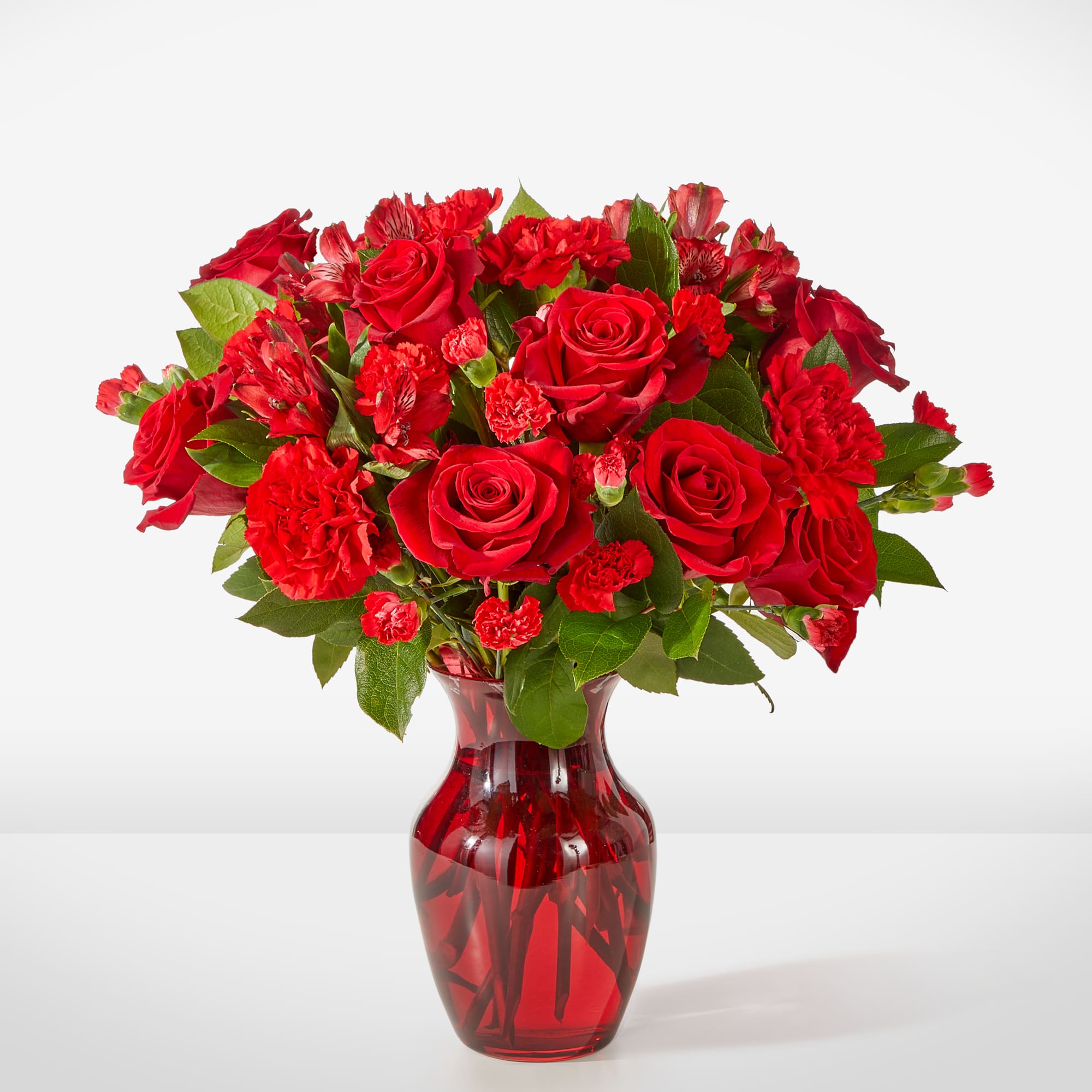 Red roses and carnations in a red glass vase