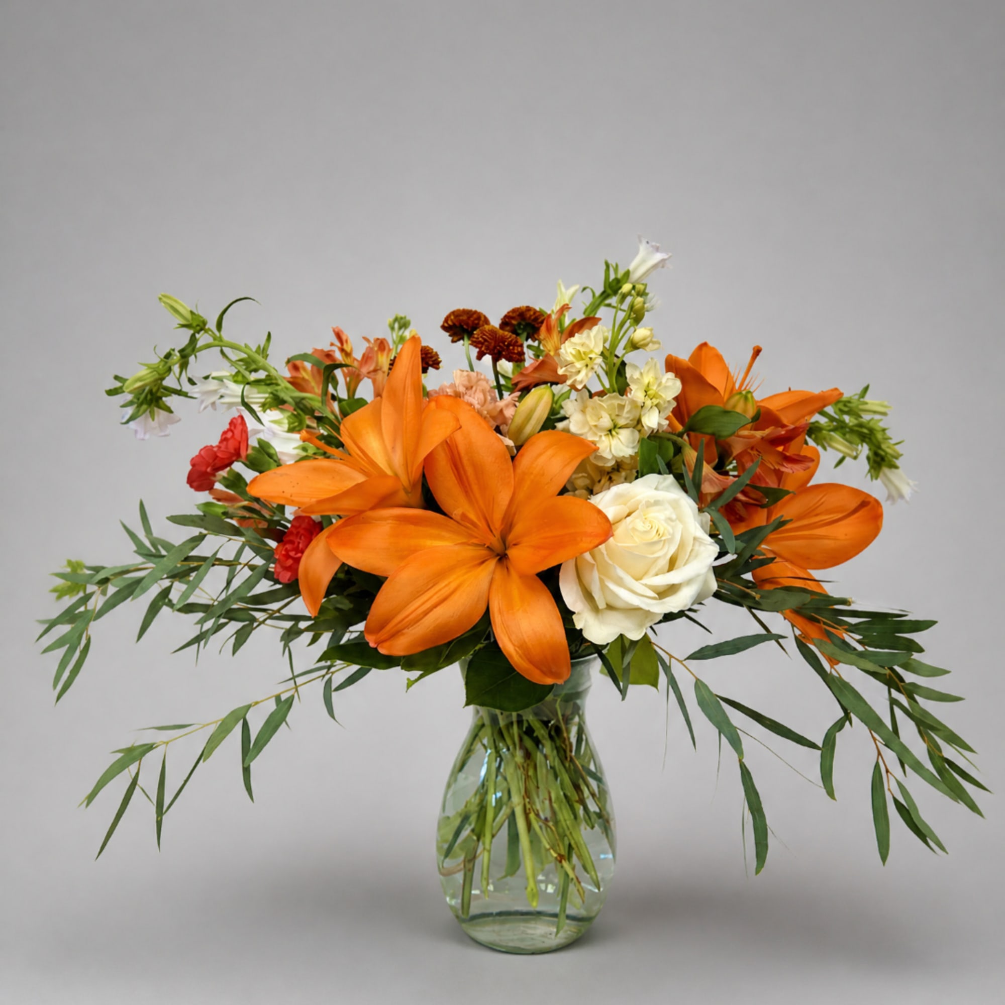 Orange lilies and white roses in a glass vase