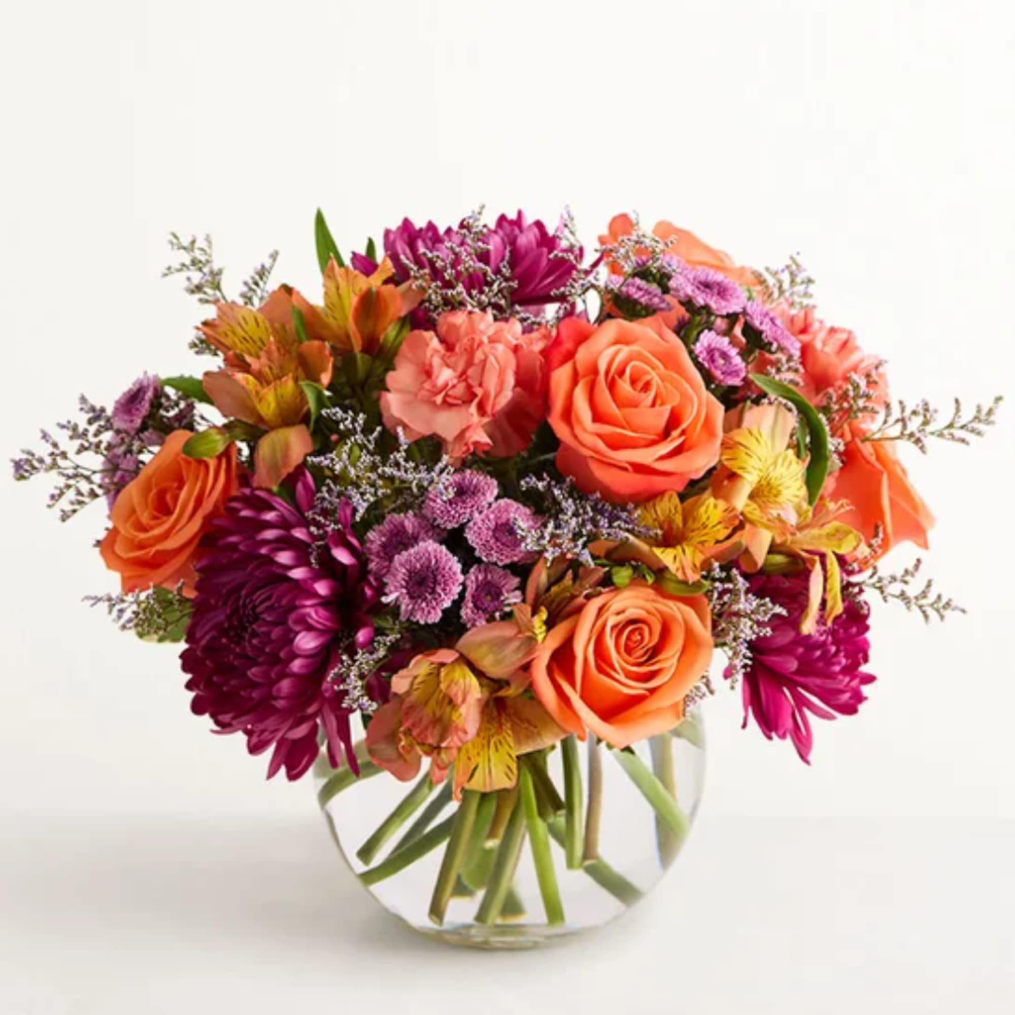 Orange and purple mixed bouquet in a clear glass vase