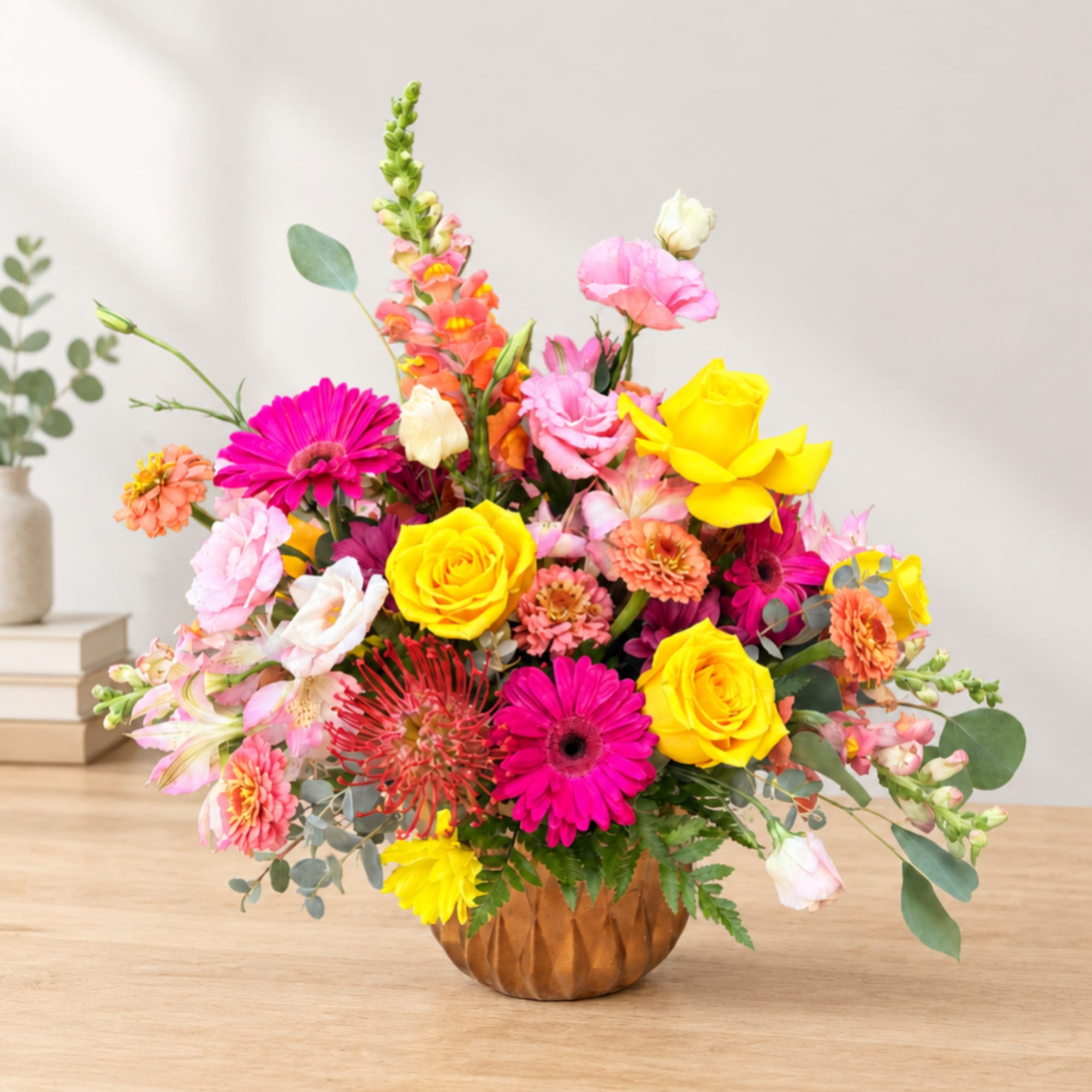 Bright mixed flower arrangement in a brown vase with pink, yellow, and orange blooms.