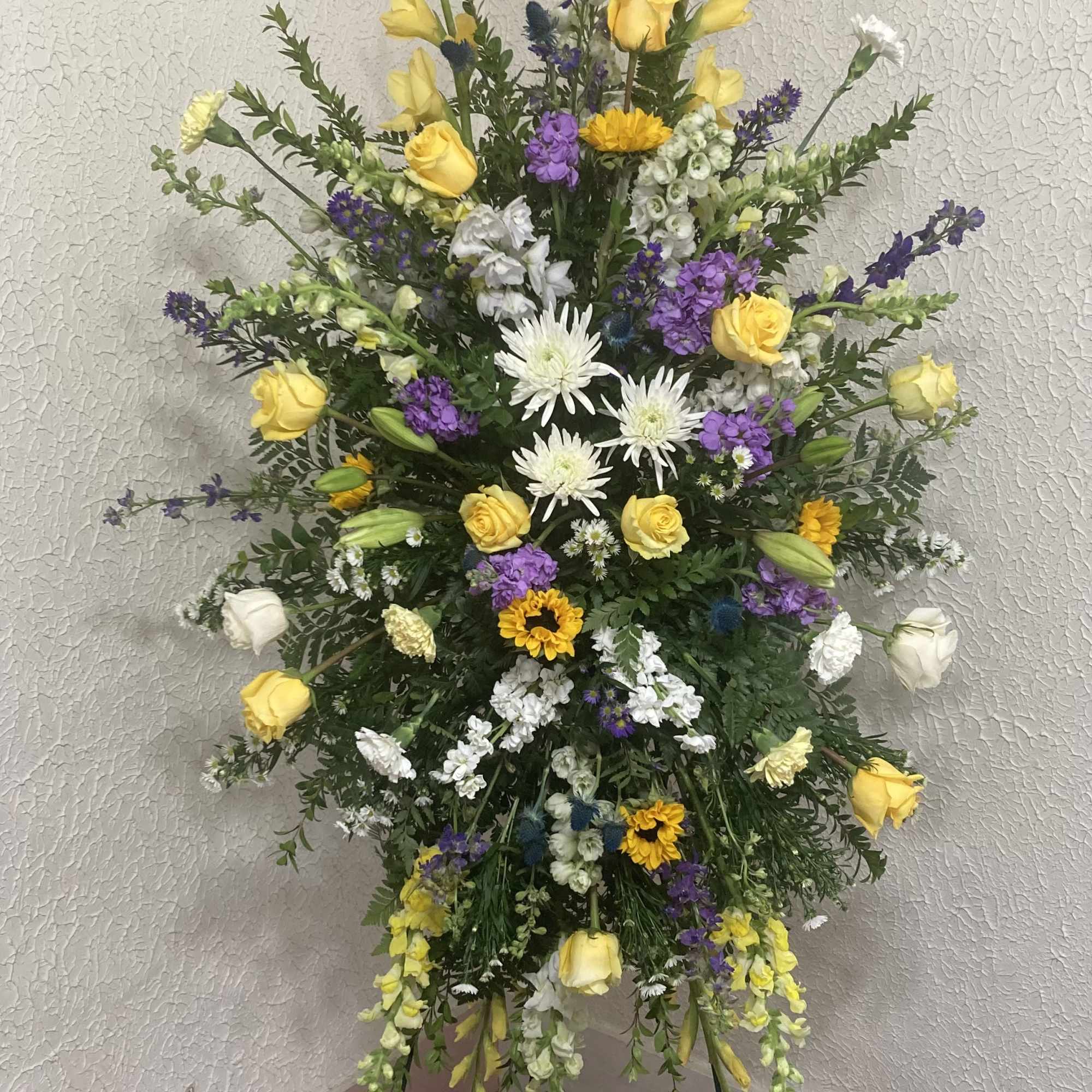 Tall standing floral spray with yellow and white blooms and purple accents
