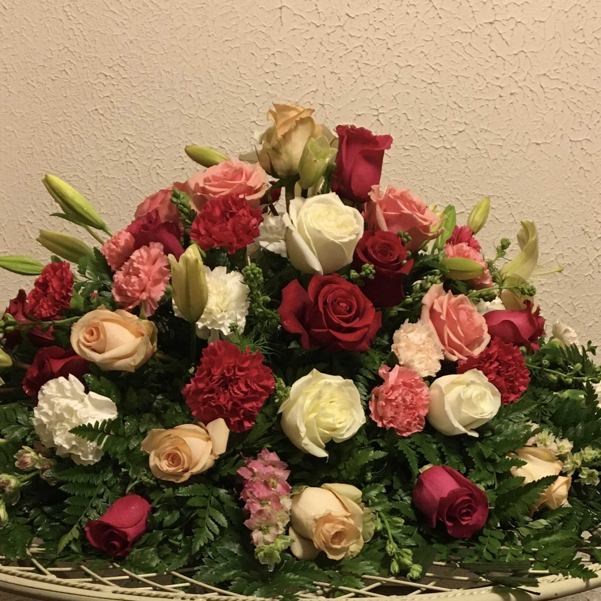 Large mixed bouquet of roses, lilies, and carnations in a shallow basket