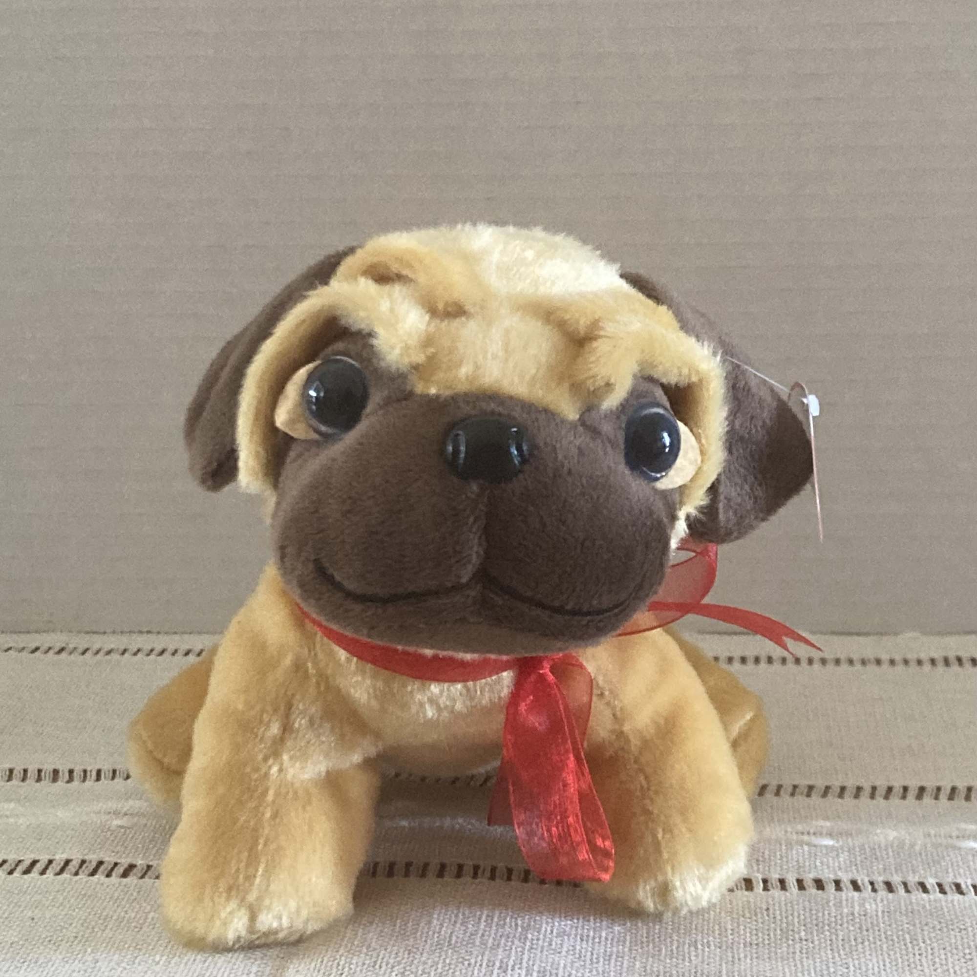 Plush pug toy with a red ribbon around its neck