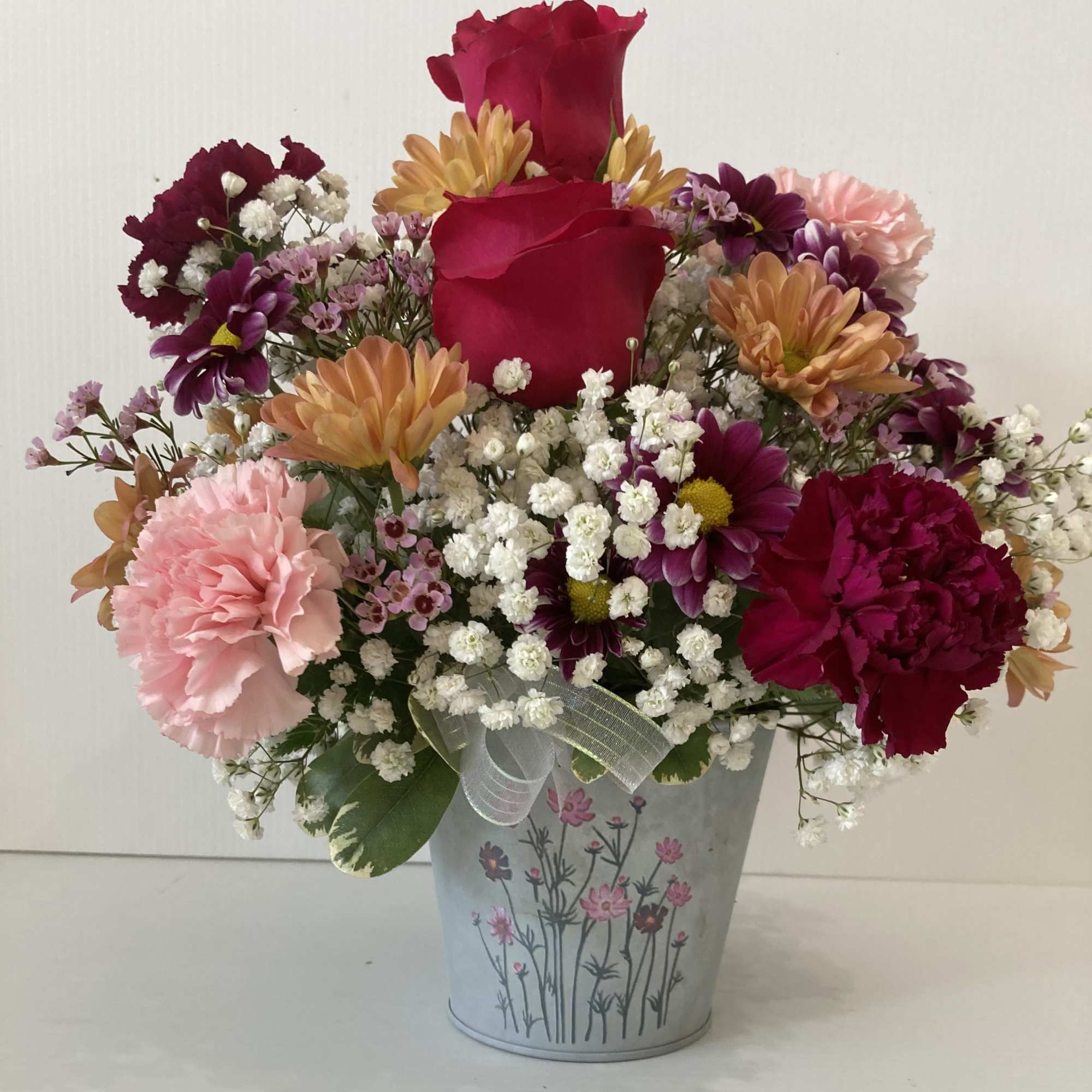 Arrangement includes roses, lilies, carnations,  daisy, filler and assorted greenery
