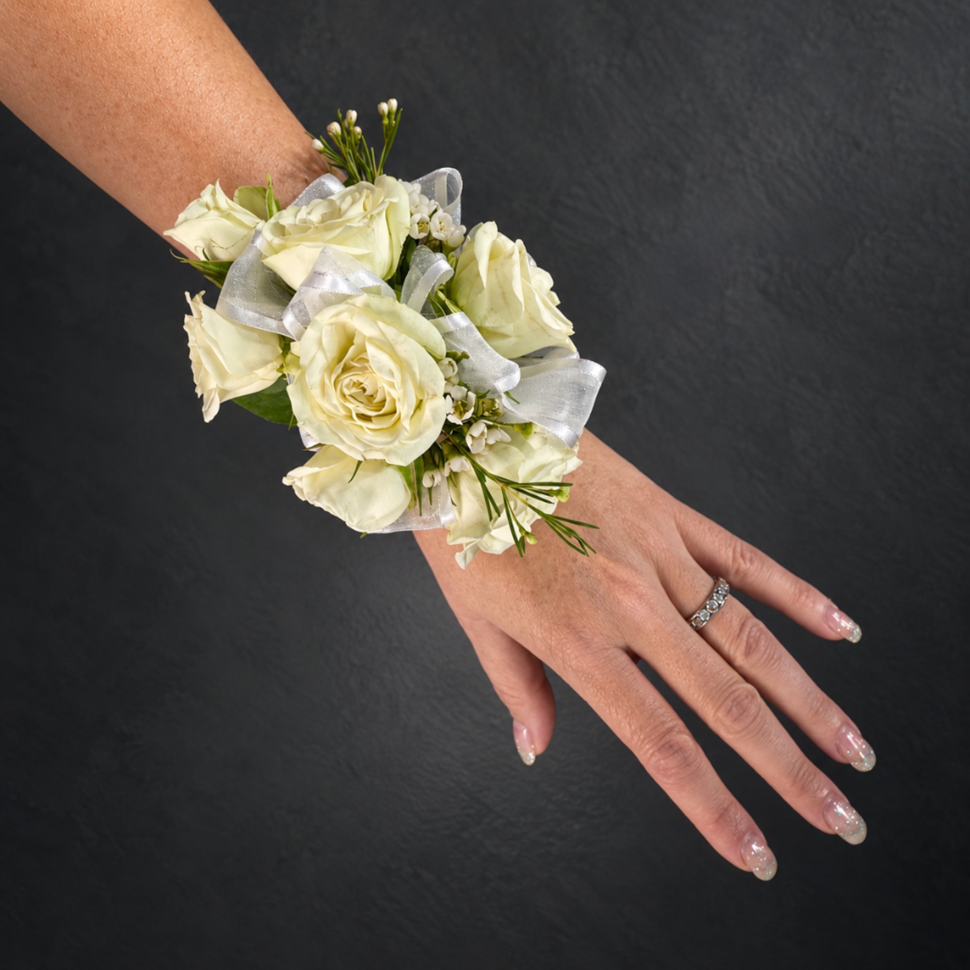 White rose wrist corsage with silver ribbon on a person's wrist