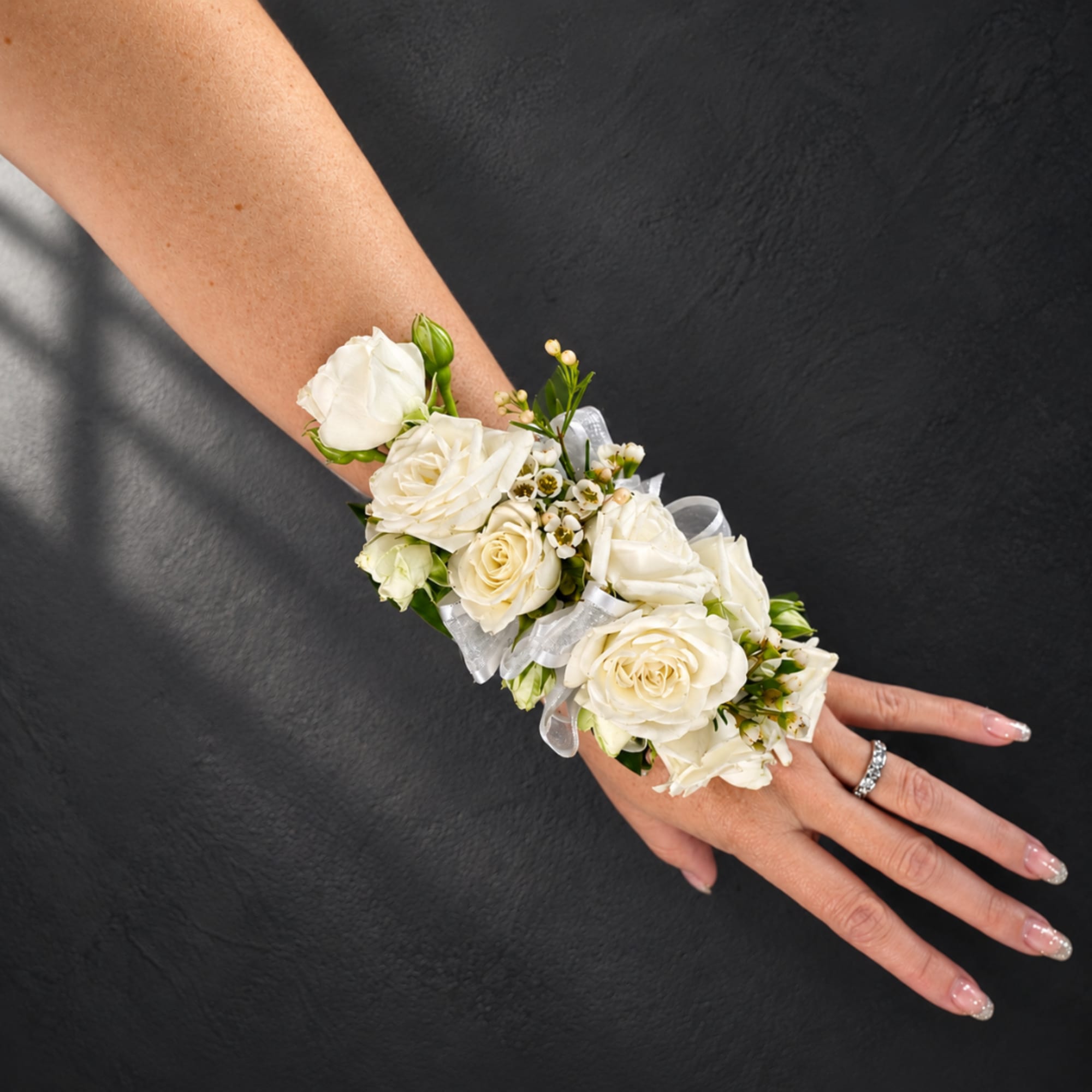 White rose wrist corsage with ribbon on a person's arm