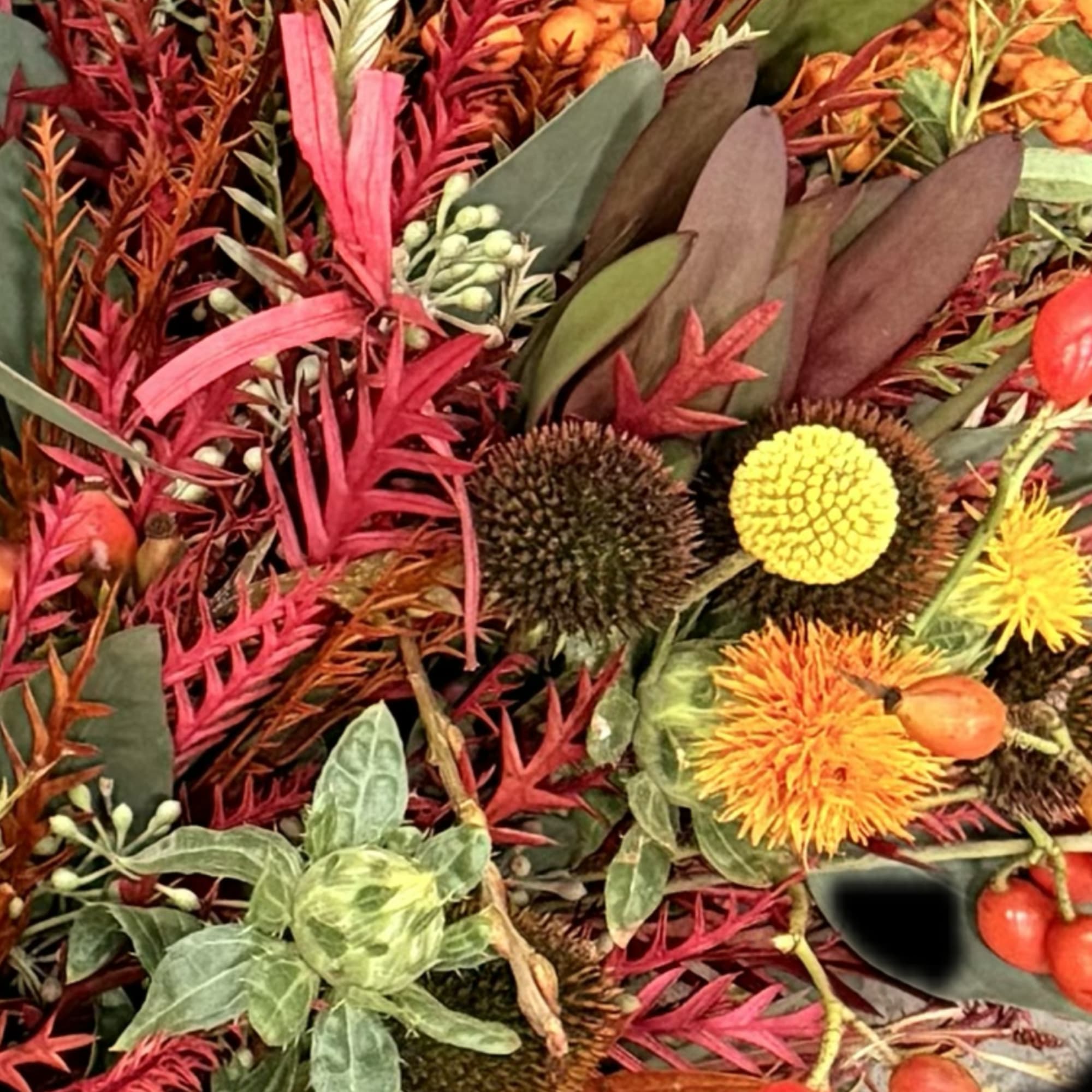 Autumn floral arrangement with orange and yellow blooms and red foliage