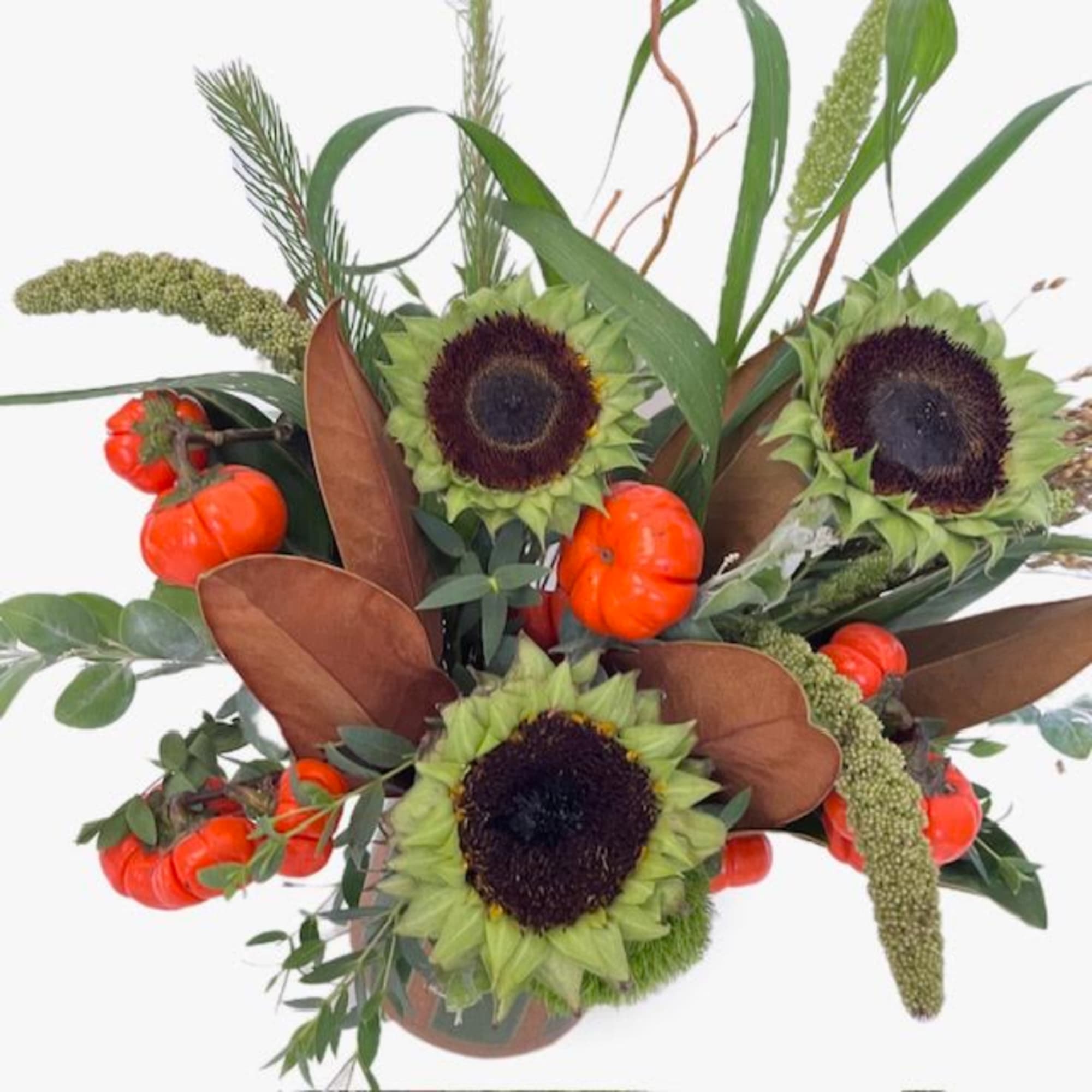 Arrangement with sunflowers, orange pumpkins, and mixed greenery in a vase