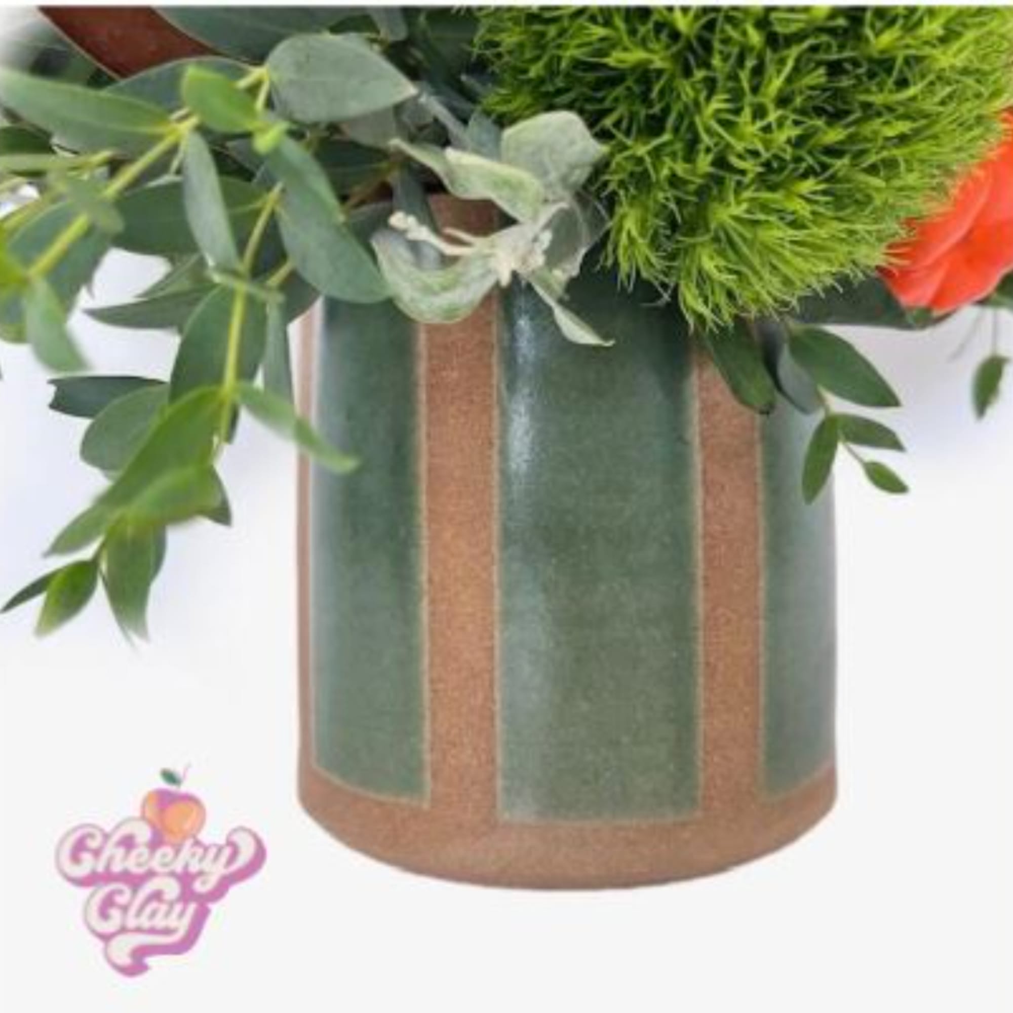 Green floral arrangement in a tall vase with orange blooms