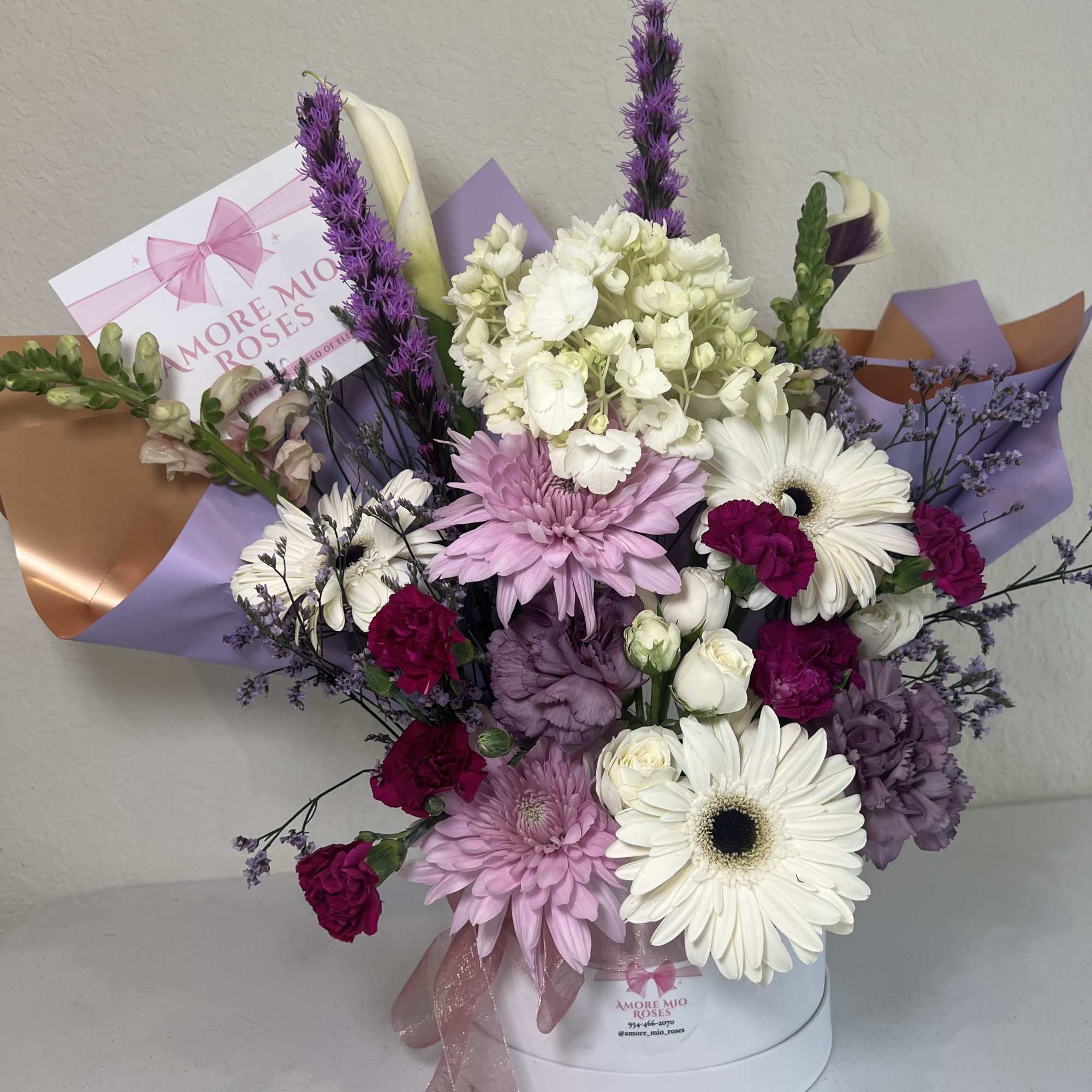 Mixed bouquet of pink, white, purple, and magenta flowers in a round box
