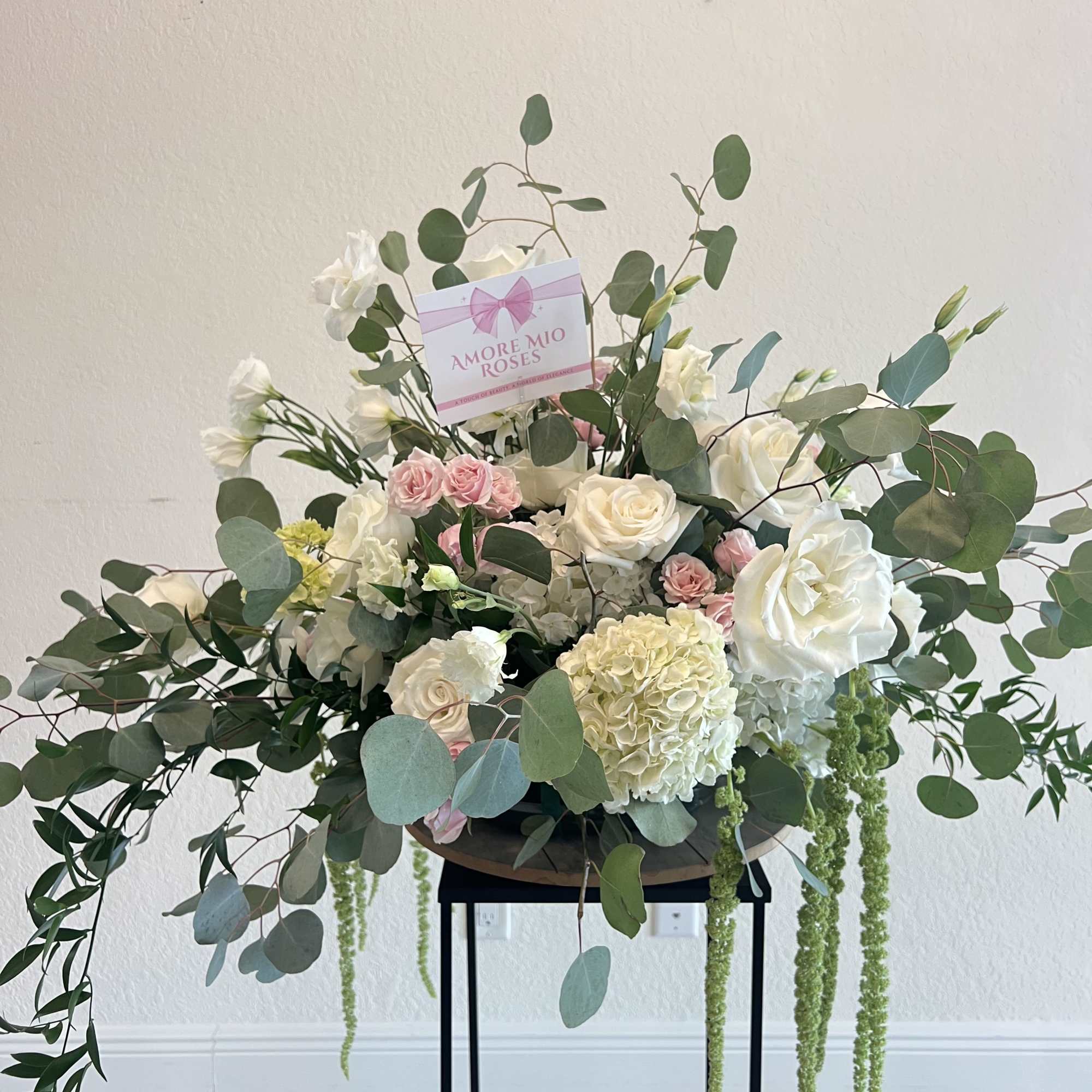 Large white and pink rose arrangement with eucalyptus and trailing greenery