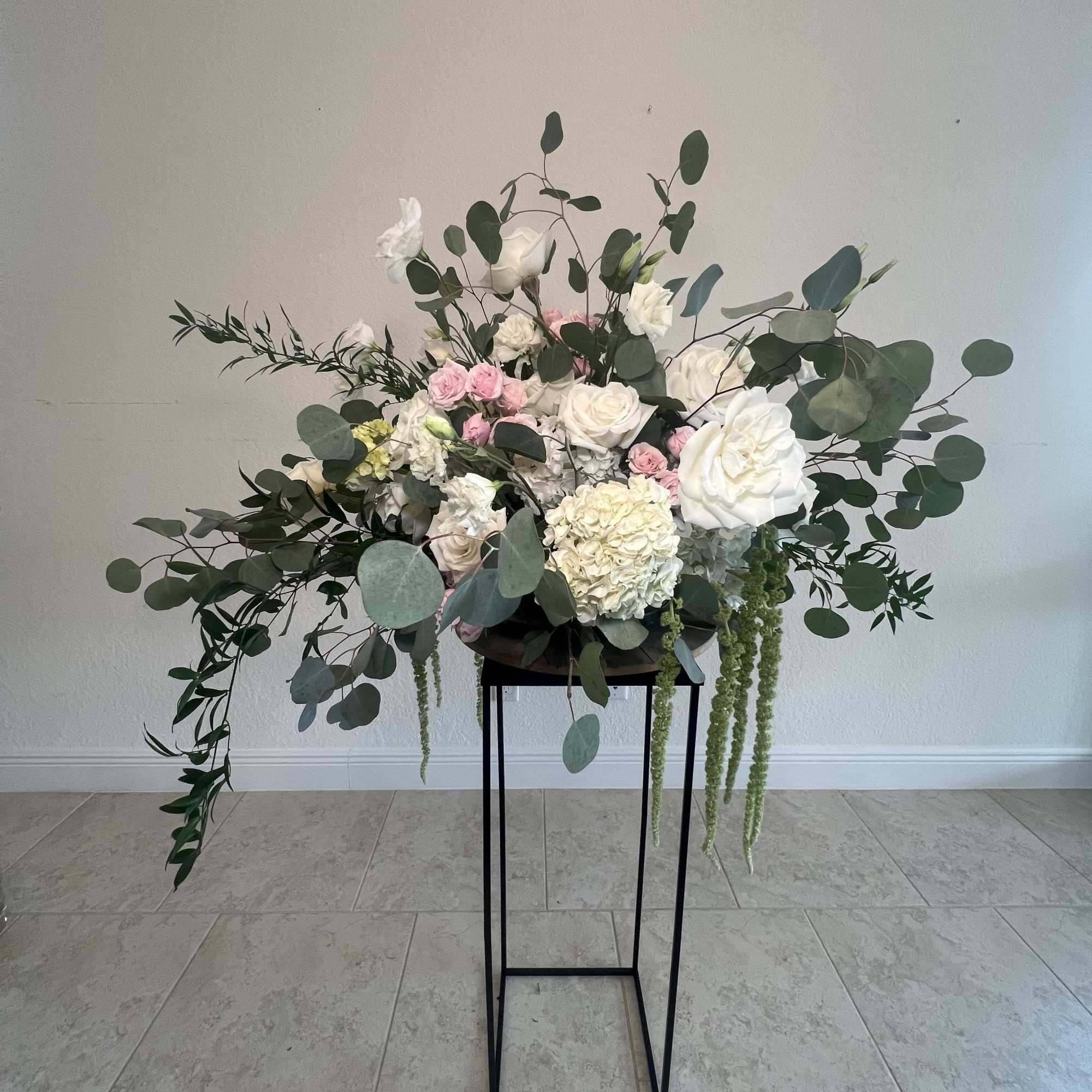 Large white and pink floral arrangement on a black stand