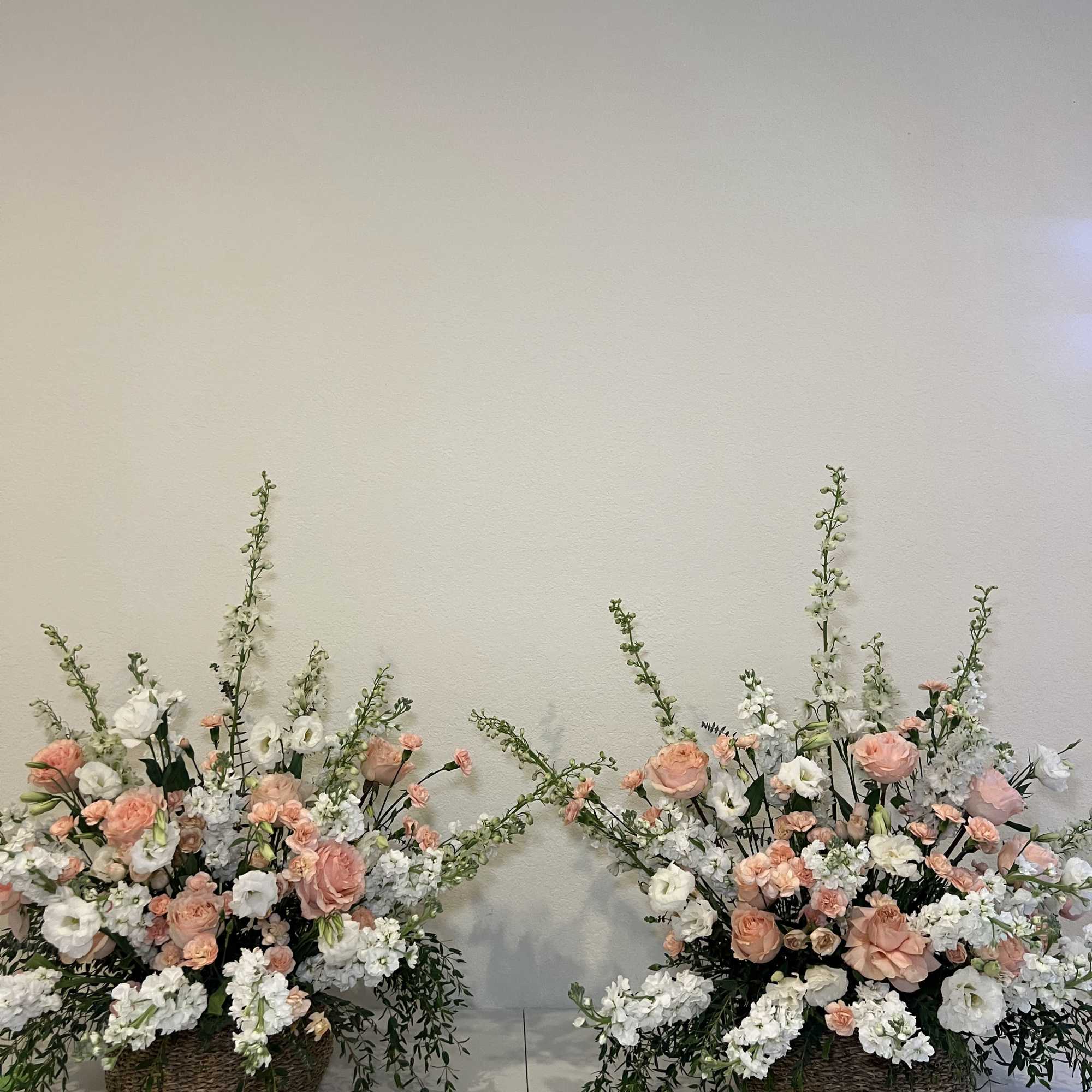 Two large floral arrangements in wicker baskets with pink and white blooms