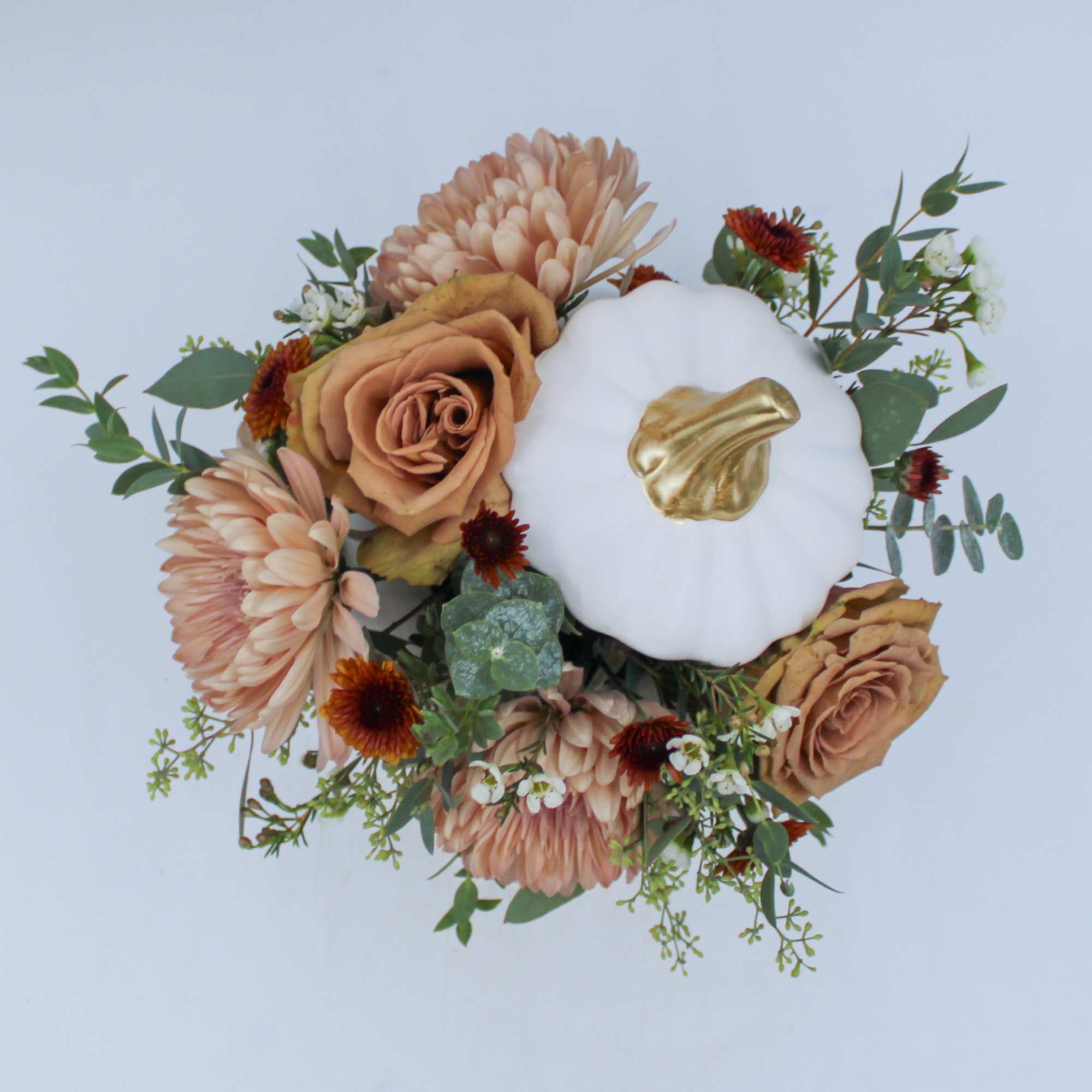 Peach flowers arranged around a white pumpkin centerpiece