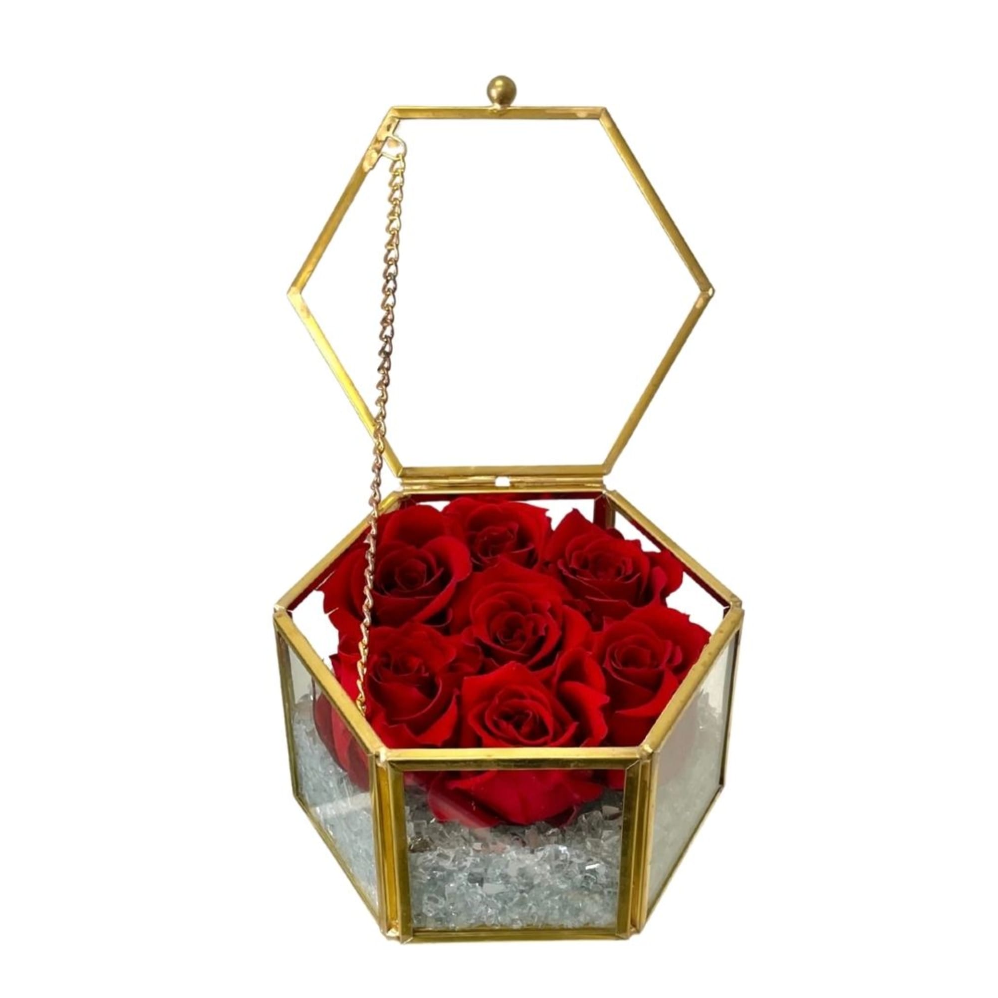 Red roses in a gold hexagonal glass box with an open lid