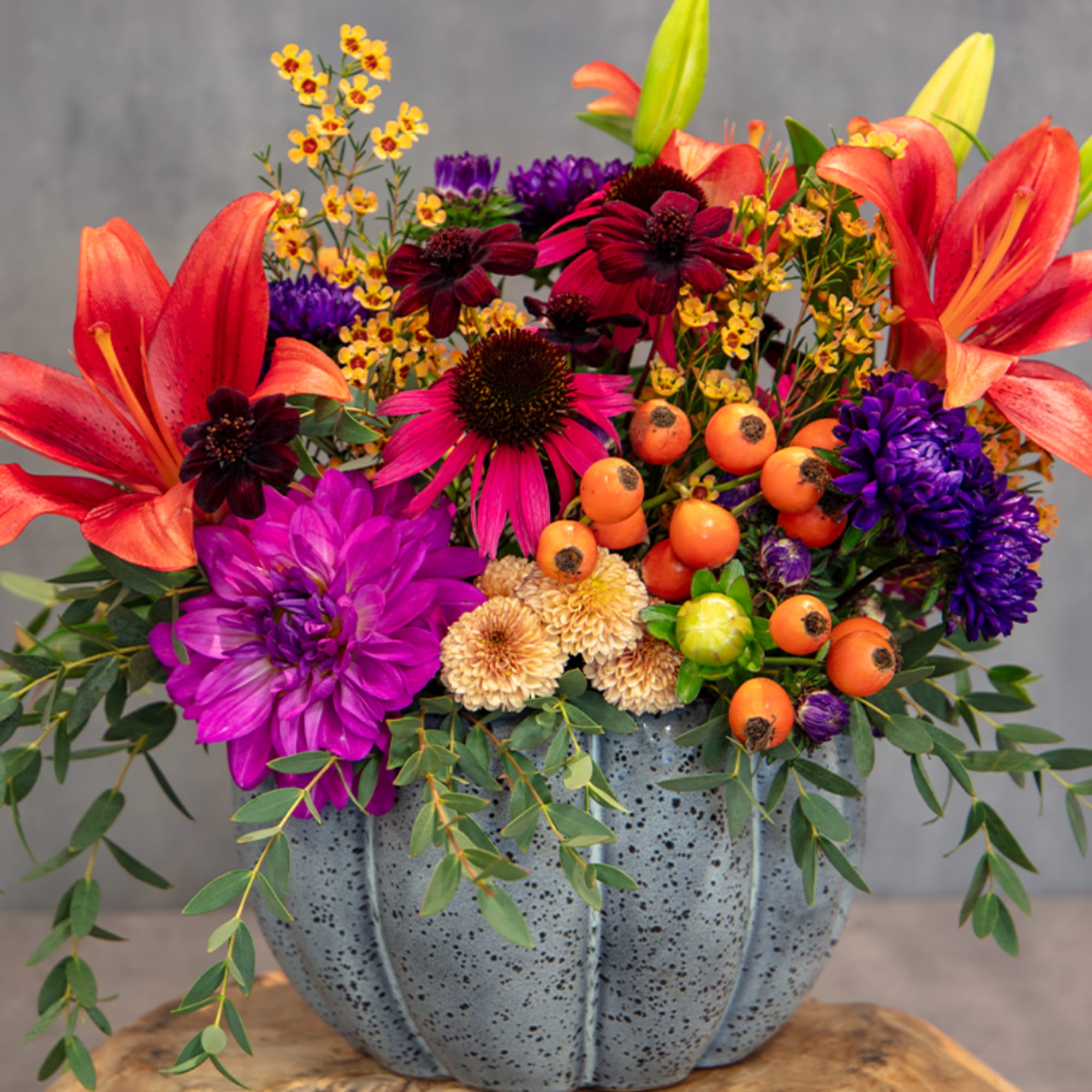 Colorful bouquet in a speckled gray pumpkin vase with lilies and dahlias