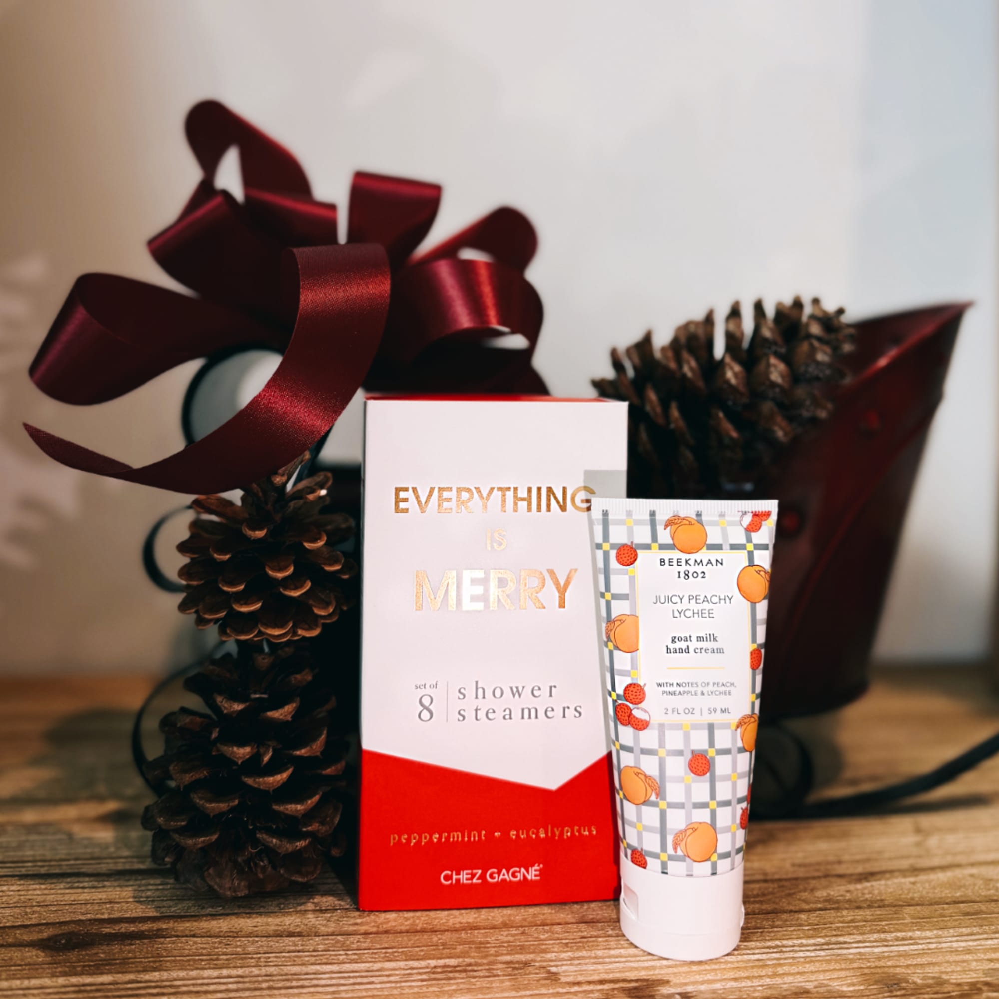 Gift set with a ribboned pinecone decoration, shower steamer box, and hand cream tube