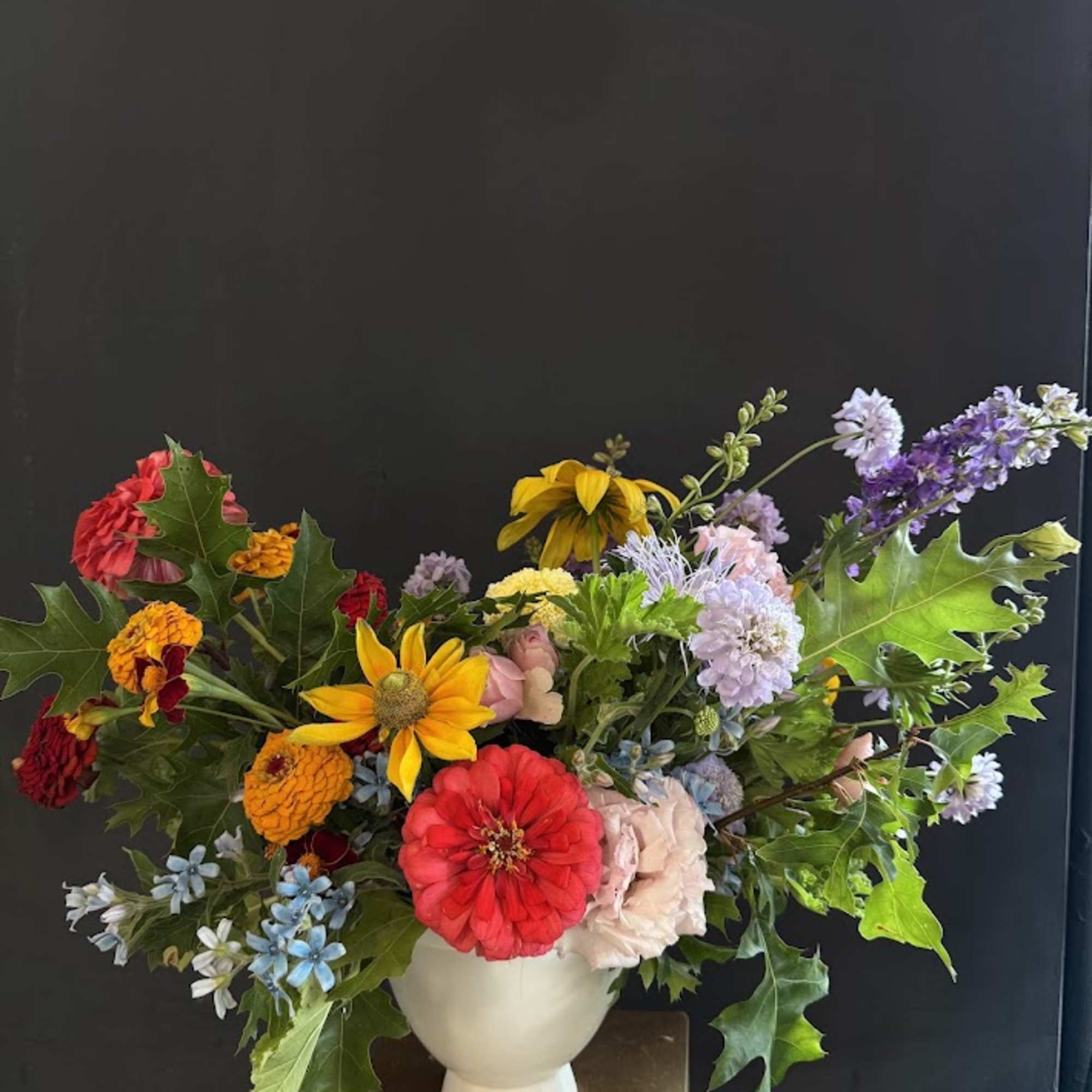 Colorful mixed bouquet in a white vase with zinnias and daisies