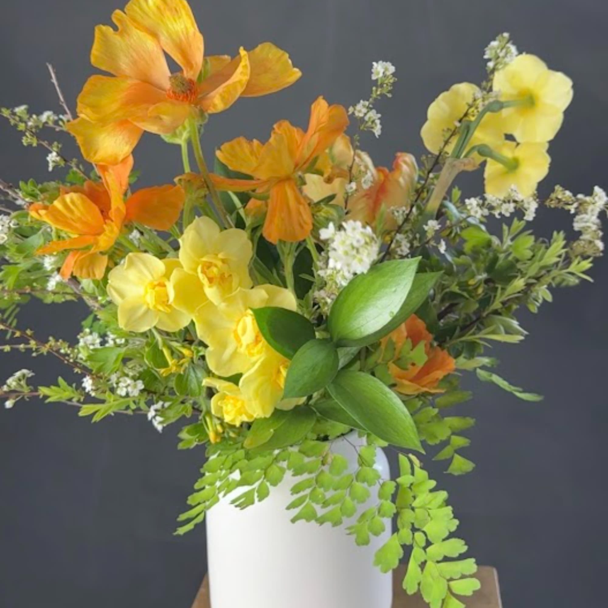 Yellow and orange flowers arranged in a white vase