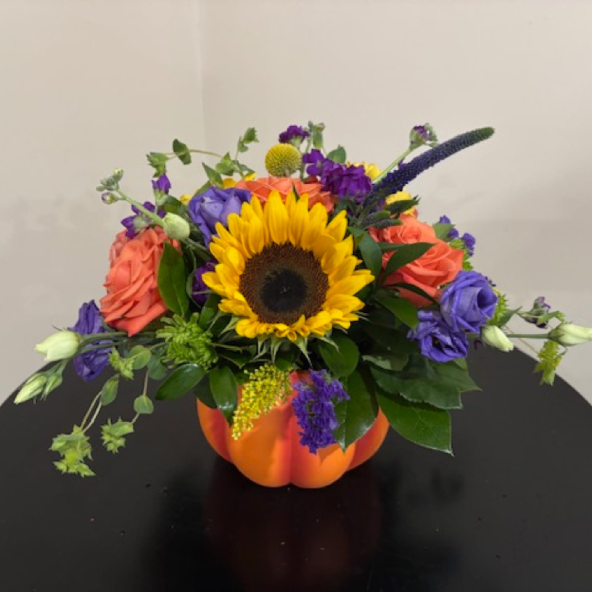 Mixed bouquet with a sunflower in an orange pumpkin vase
