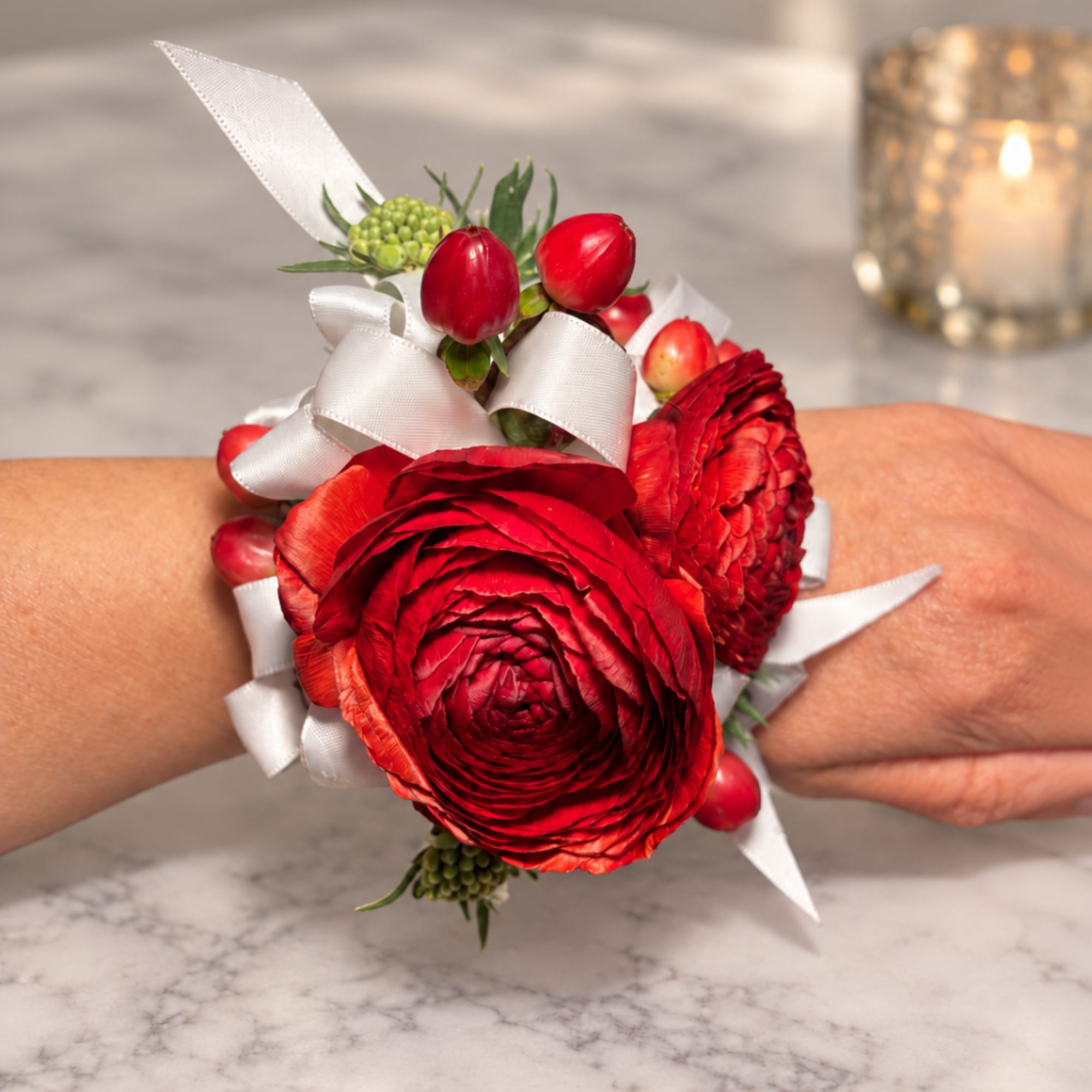 Red floral wrist corsage with white ribbon on a person's wrist
