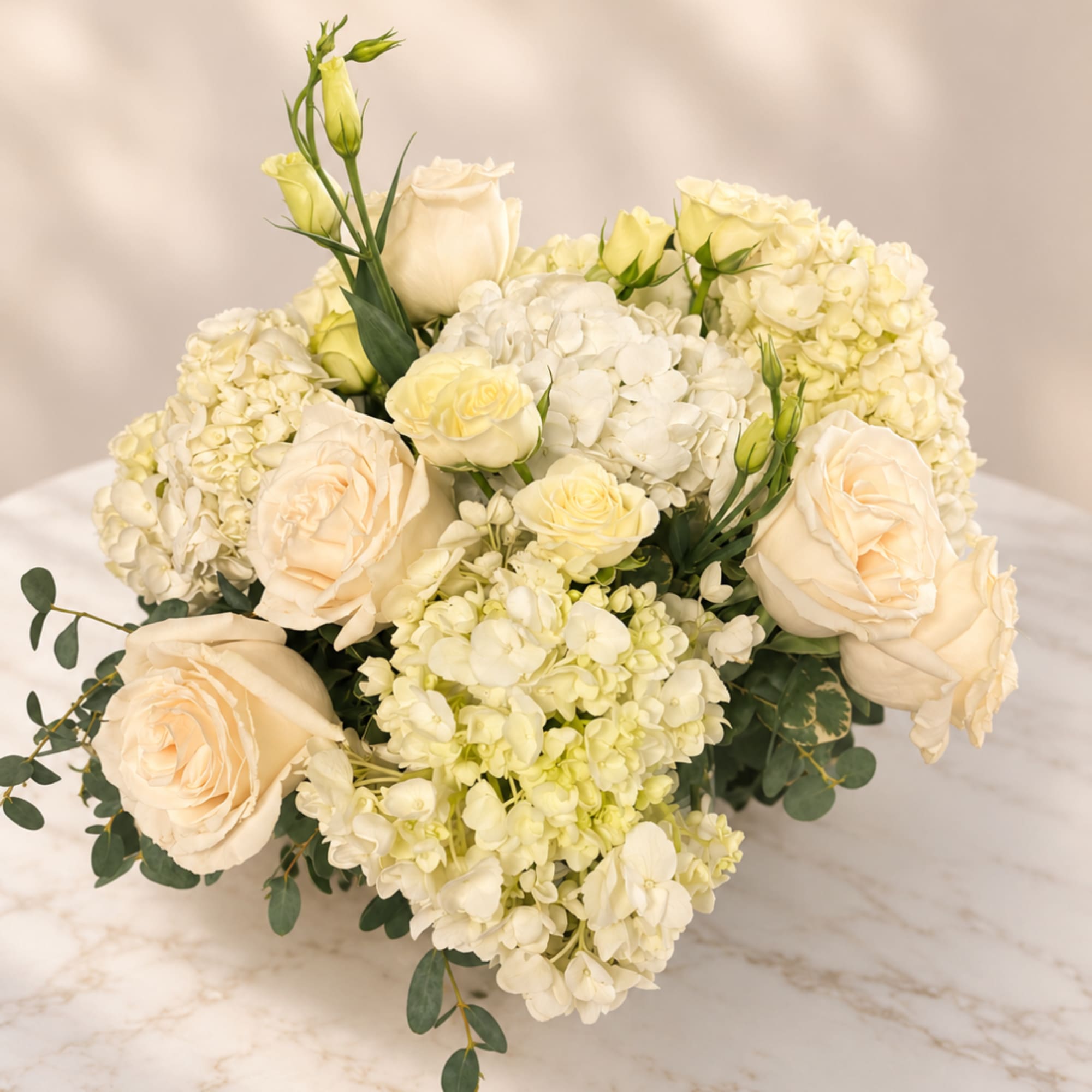 Cream roses and white hydrangeas arranged in a low bouquet