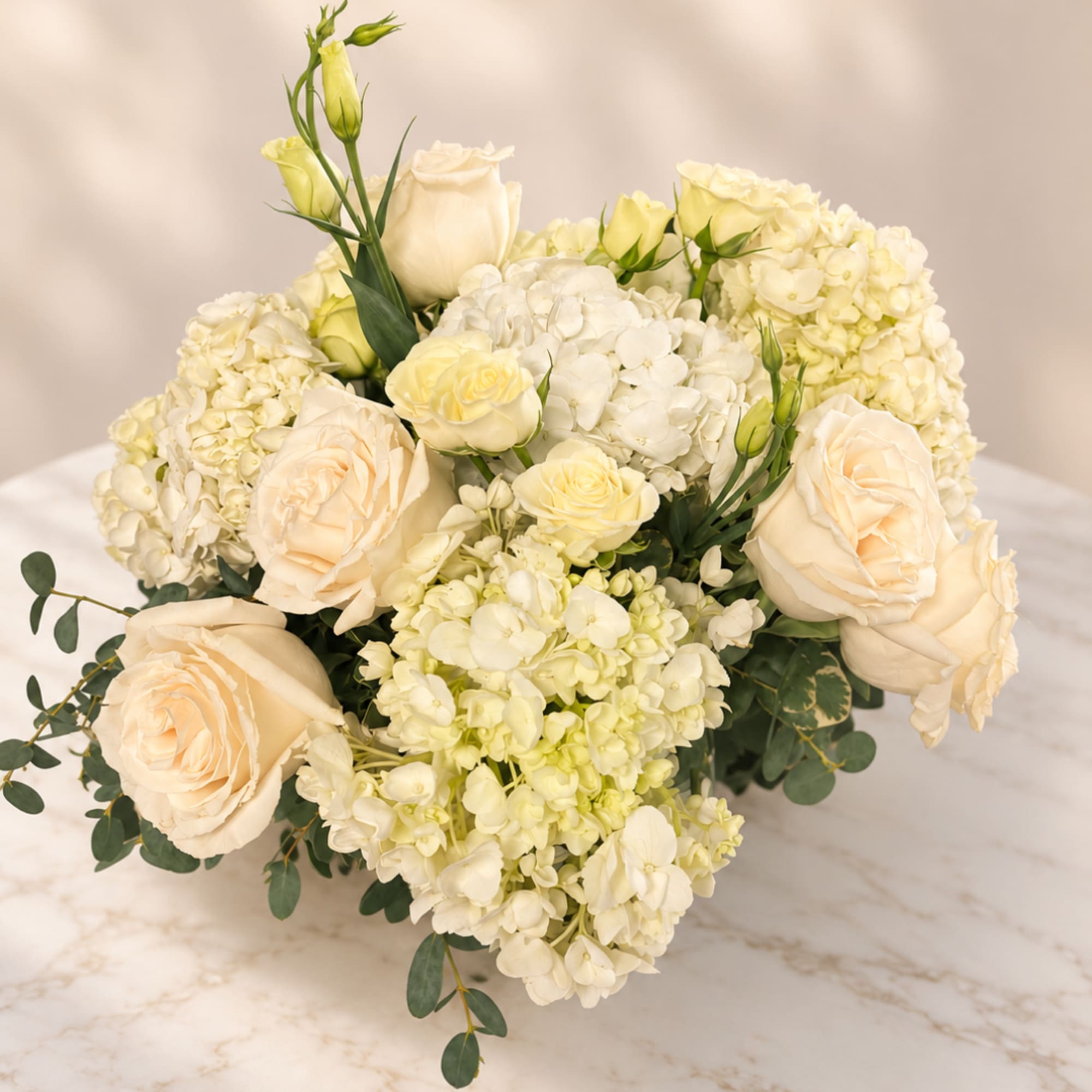 Cream roses and white hydrangeas arranged in a low bouquet
