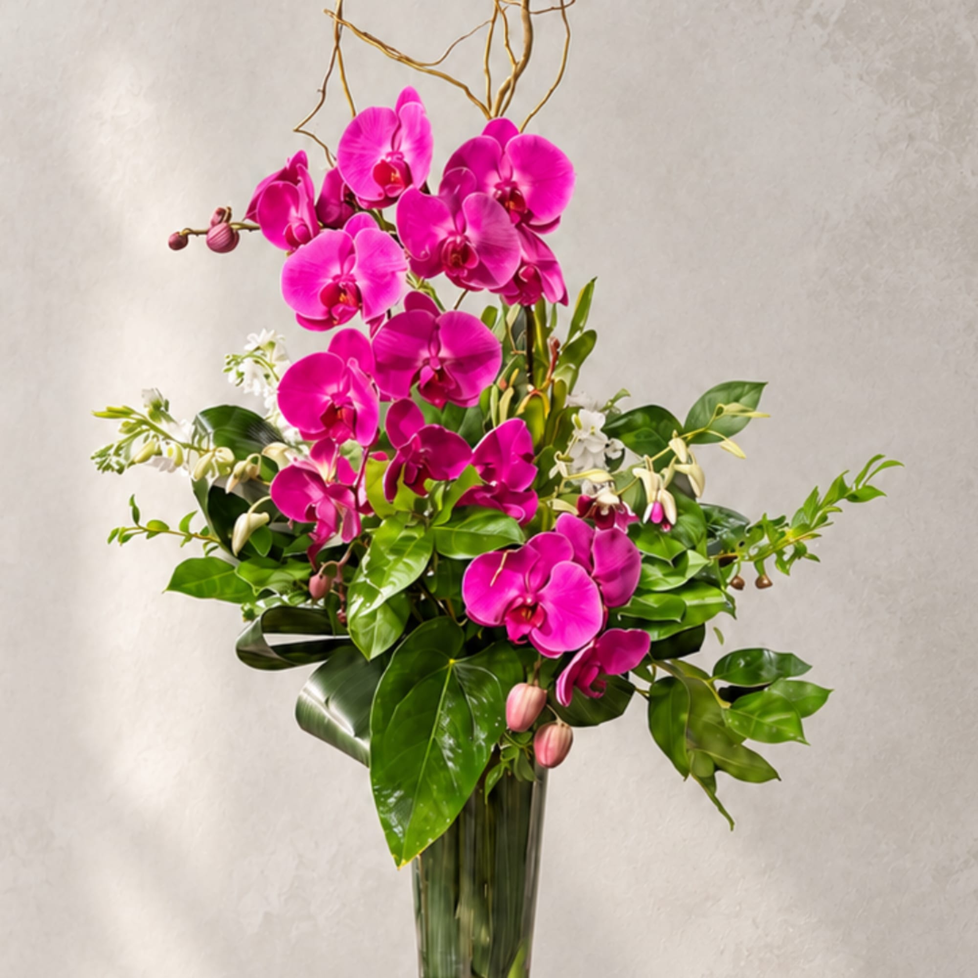 Bright pink orchids arranged in a tall glass vase with glossy greenery