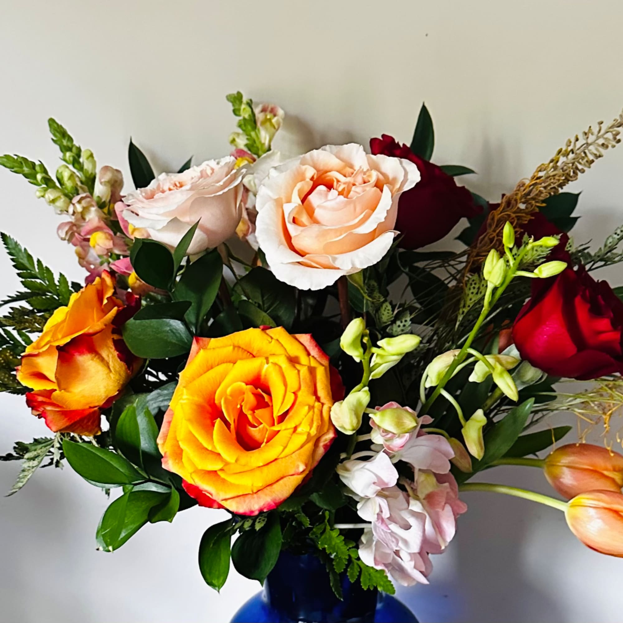 Mixed roses and snapdragons in a blue vase
