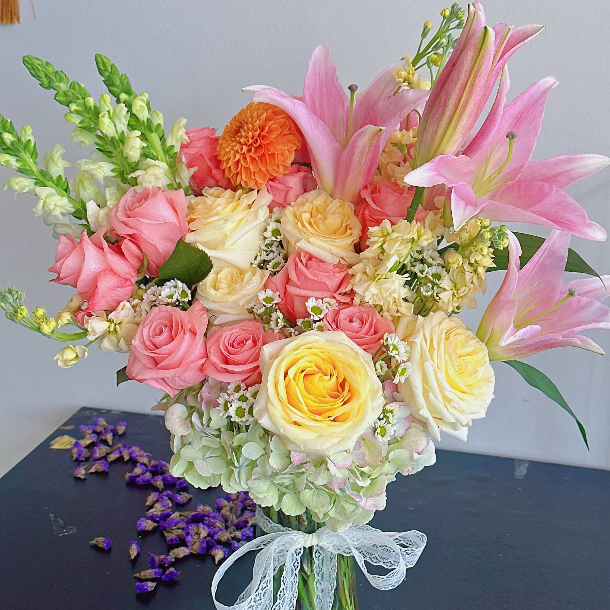 Bouquet of pink and yellow roses with pink lilies in a glass vase
