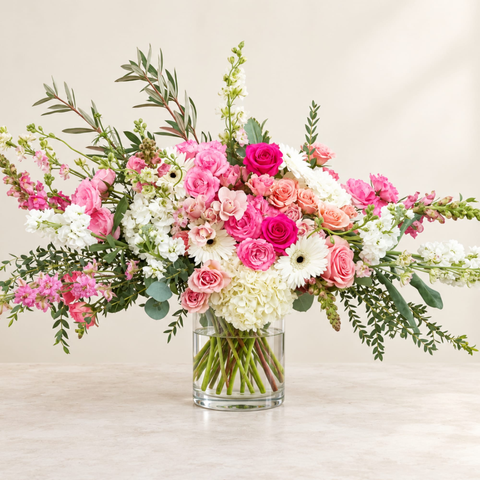 Large pink and white mixed flower arrangement in a clear glass vase