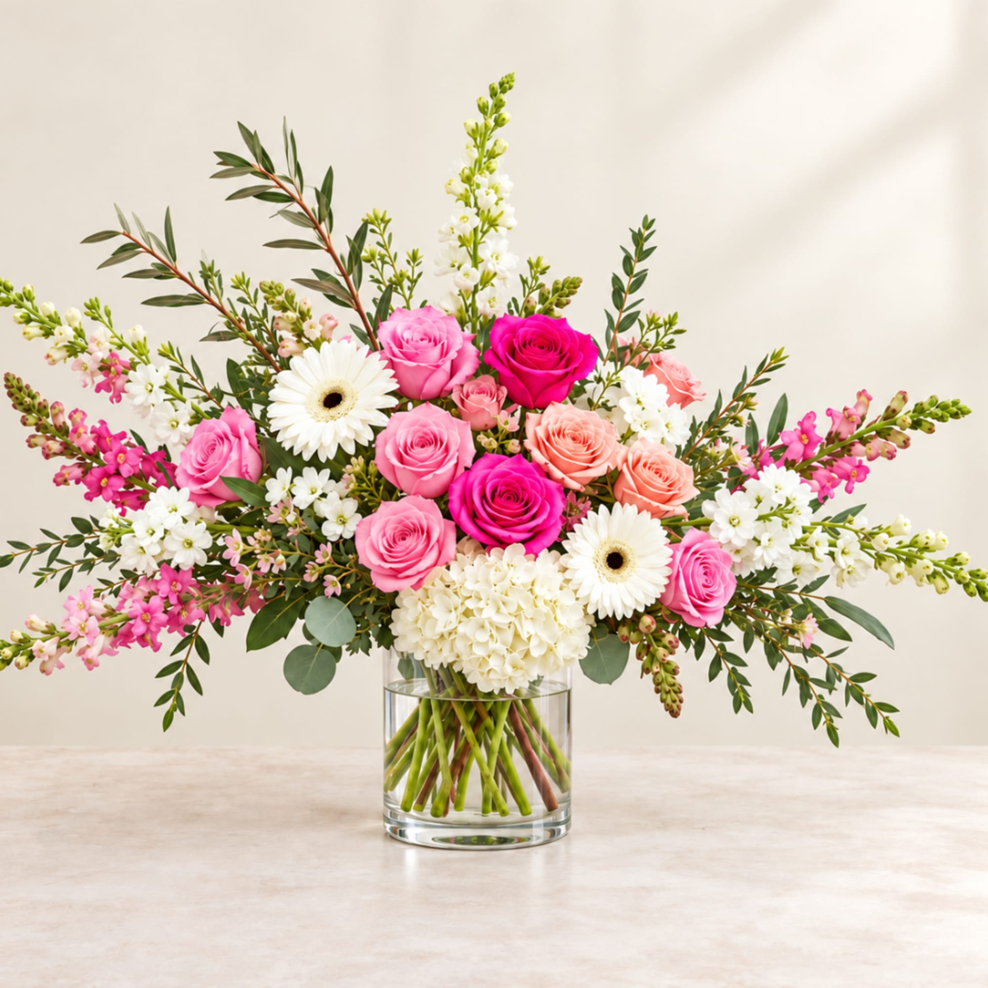 Pink and white roses with daisies in a clear glass vase