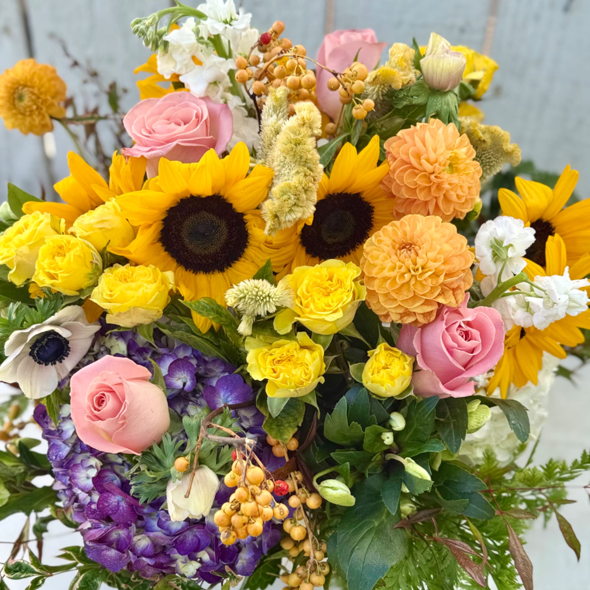 Mixed bouquet with sunflowers, pink roses, yellow blooms, and purple hydrangea