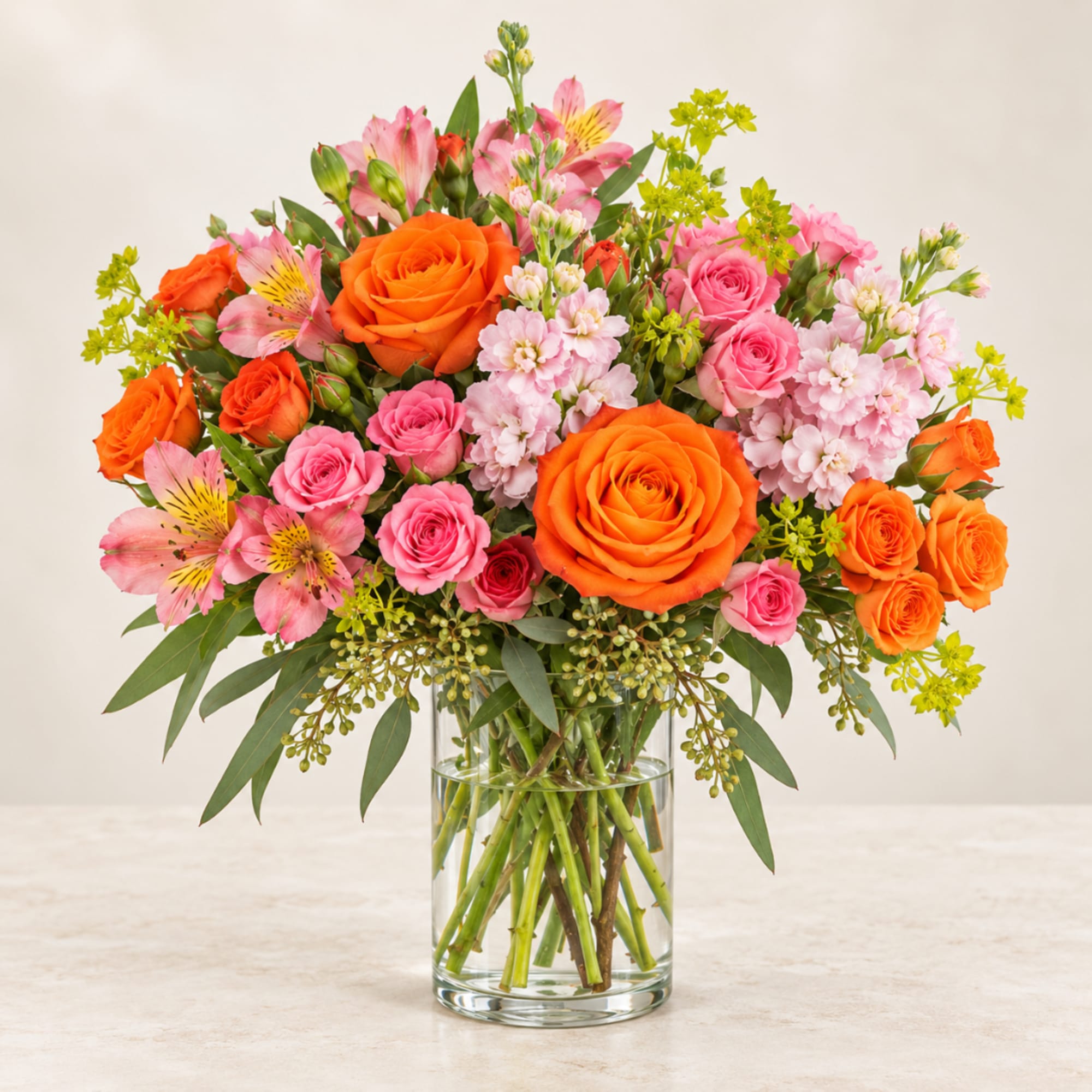 Bouquet of orange and pink roses in a clear glass vase