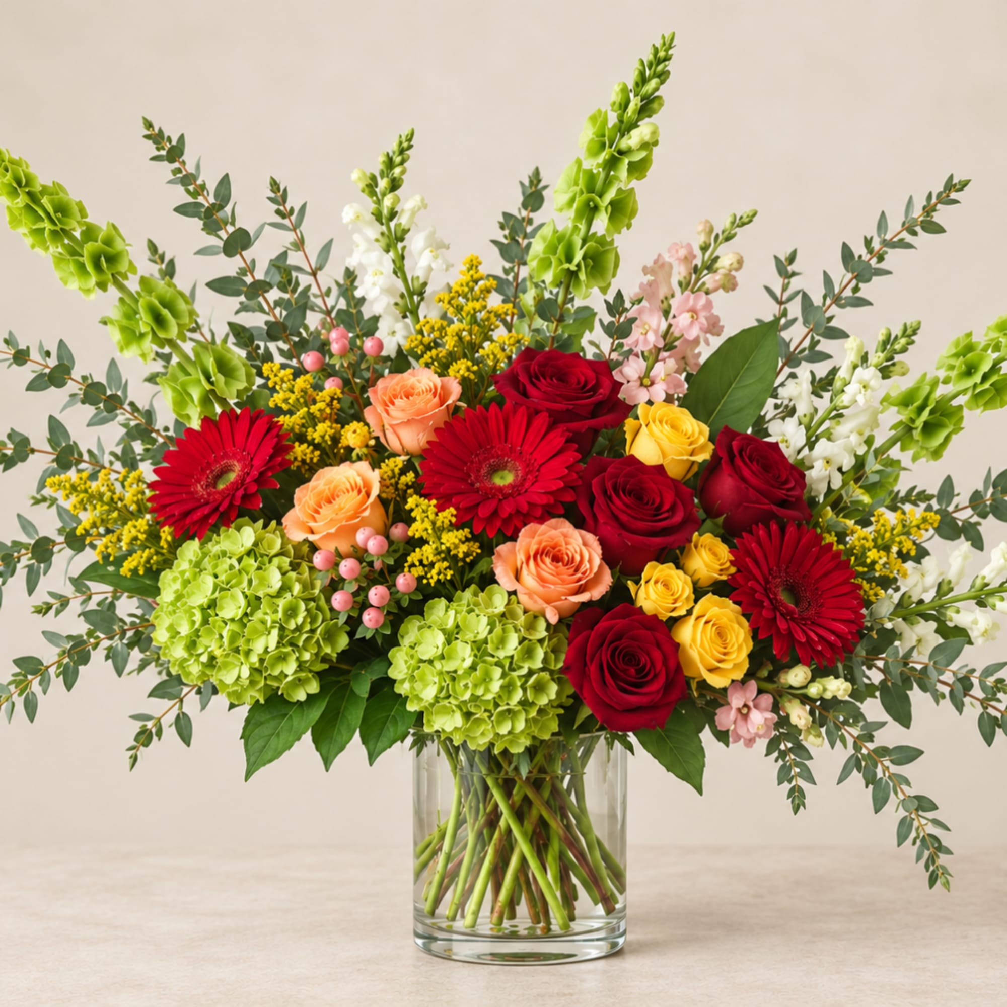Mixed bouquet of roses, gerbera daisies, and hydrangeas in a clear glass vase